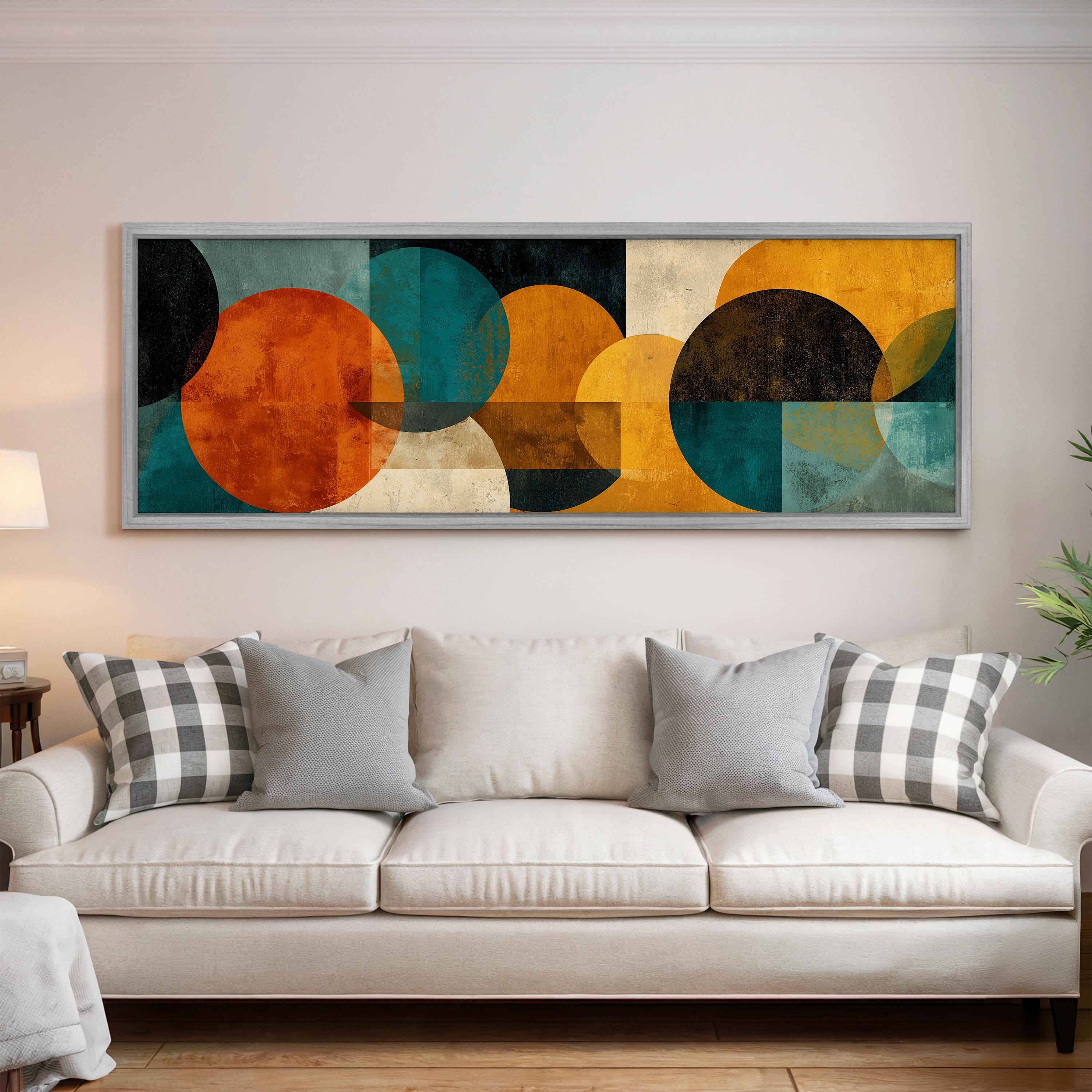 a large abstract painting hanging on a wall above a white couch with gray and white plaid throw pillows.