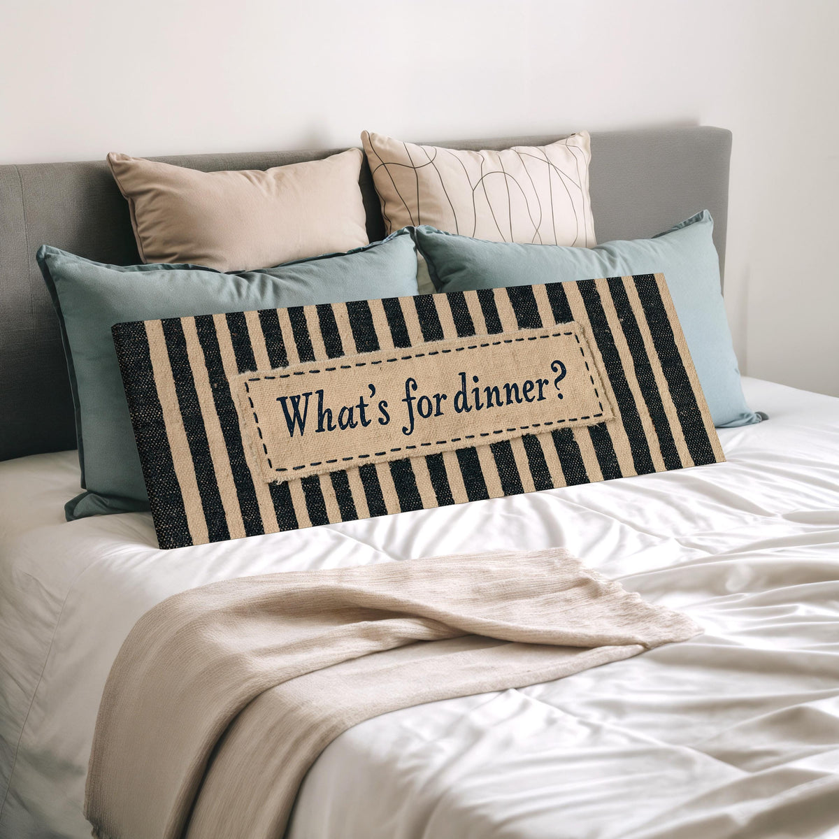What's for dinner sign on black stripes wide panoramic canvas print laid on a bed to show its size
