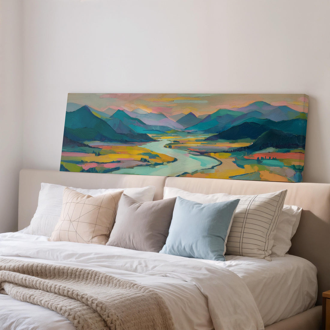 a large, colorful landscape painting hanging on a wall above a wooden dining table with four chairs. The painting depicts a scenic mountain range with a winding river, creating a serene and picturesque atmosphere.
