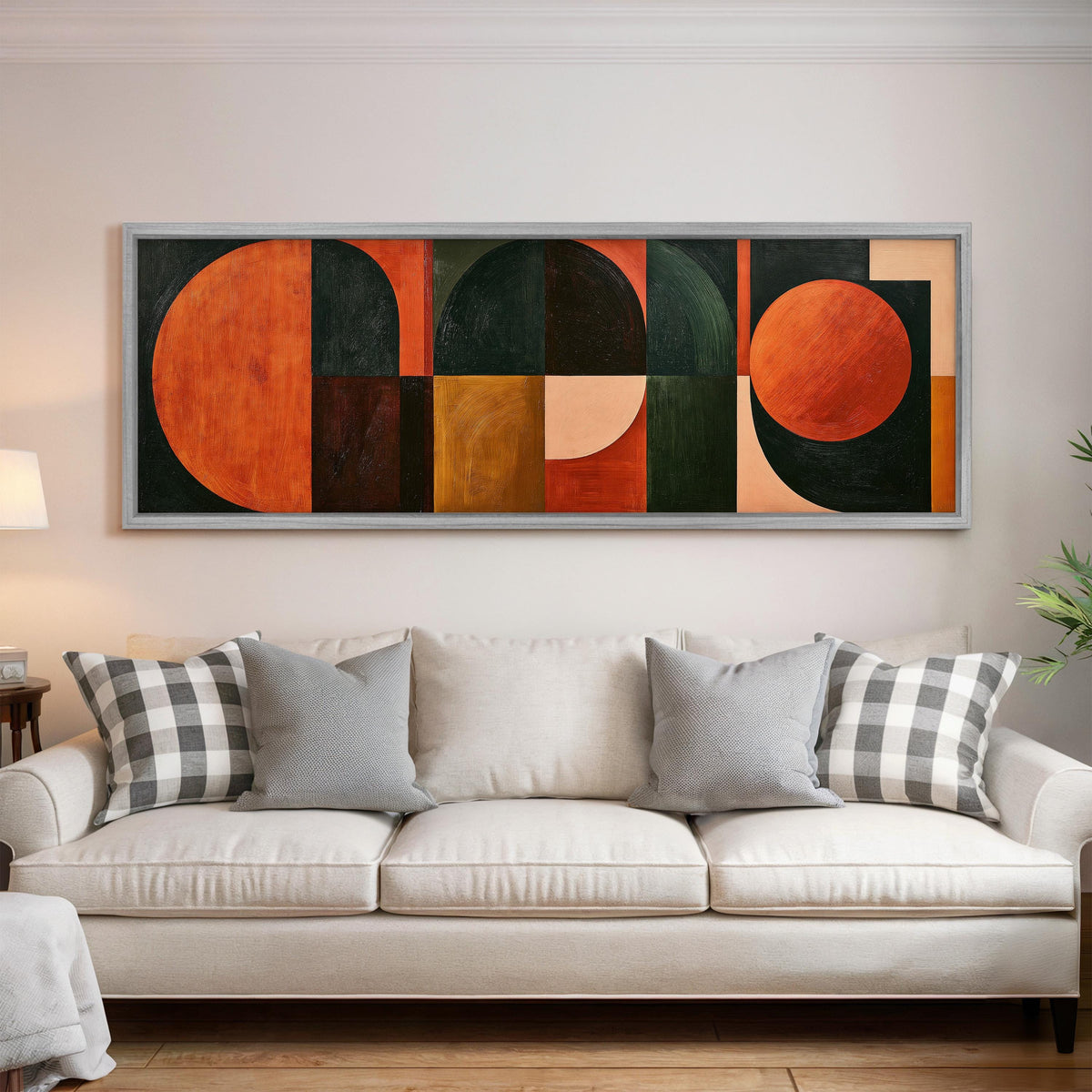 Orange circles and arches on forest green panoramic canvas print above a white sofa in a bright living room