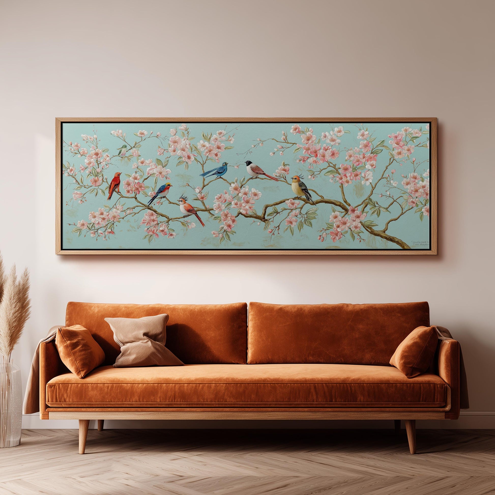 a large, framed painting of a cherry blossom tree with birds perched on its branches, hanging on a wall above a brown sofa.