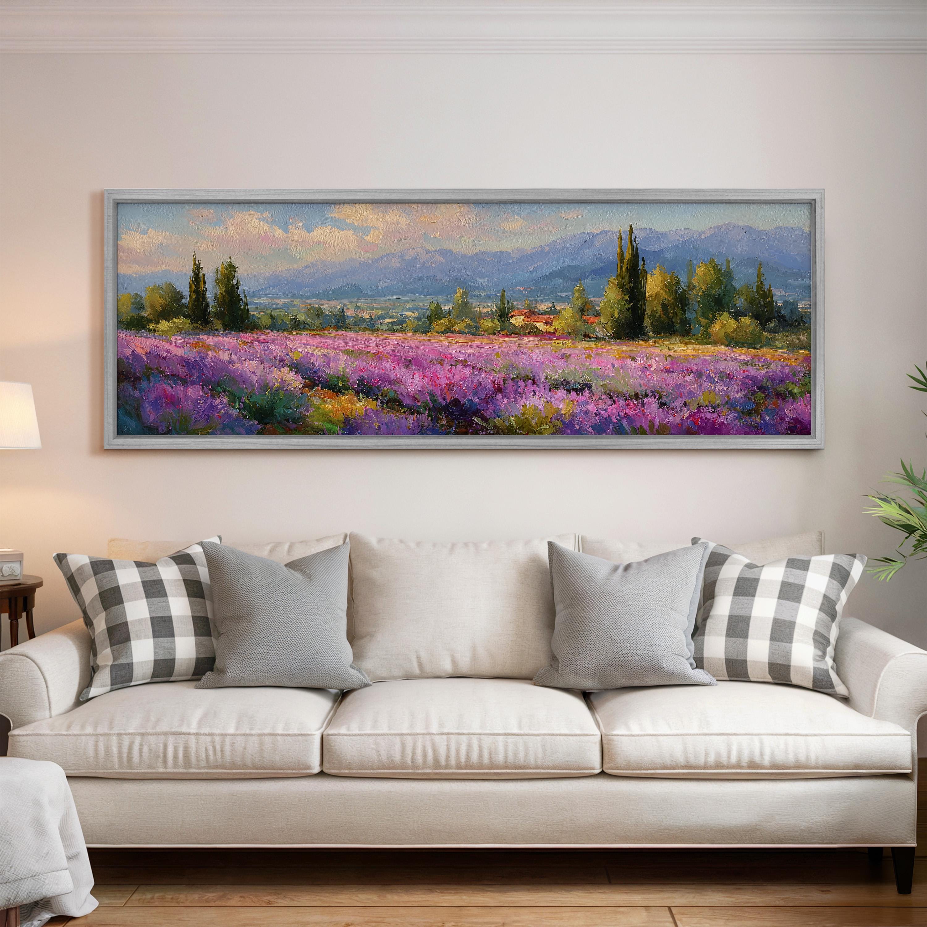 a large, framed painting of a field of purple flowers hanging on a wall above a white couch with gray and white patterned pillows.