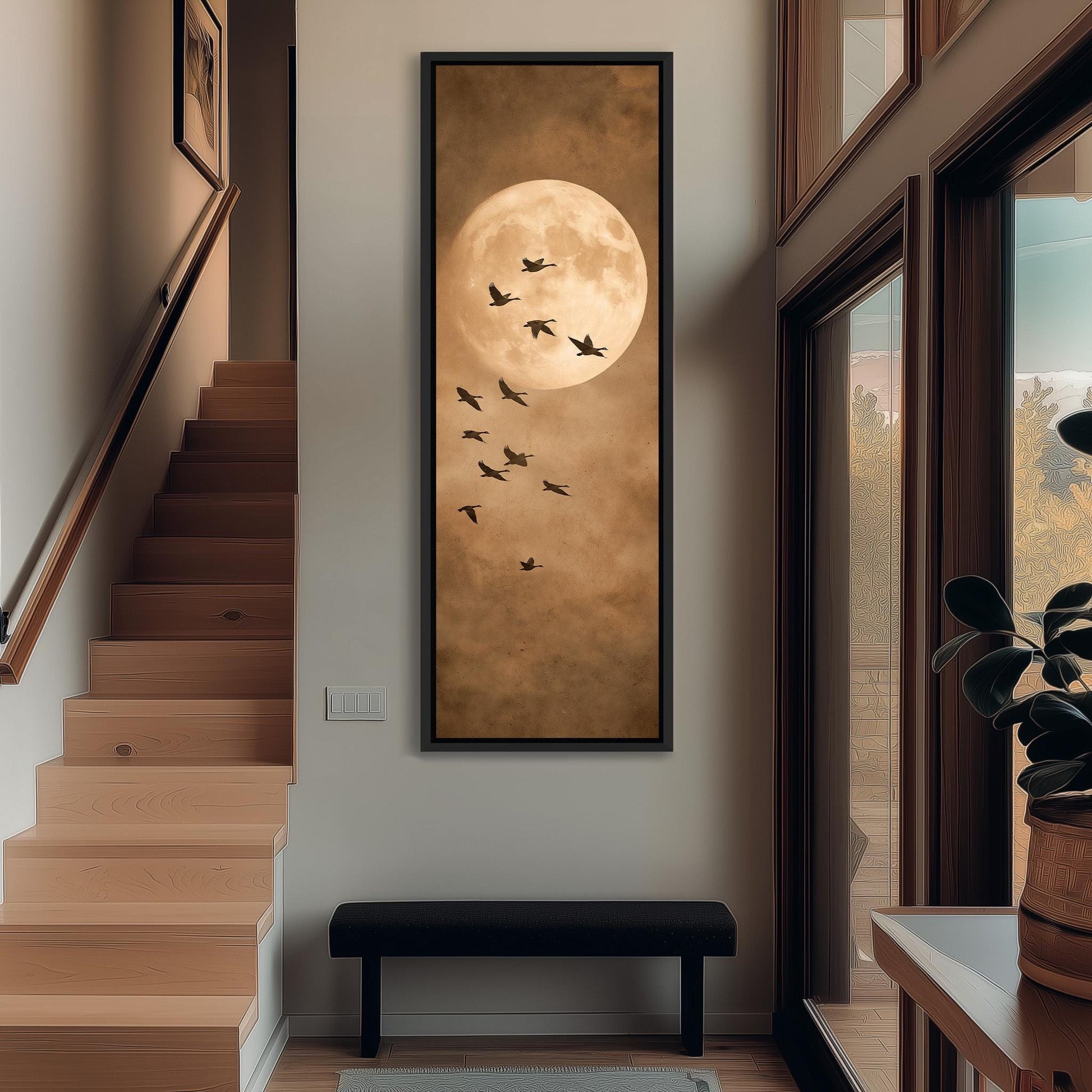 a large framed picture of a full moon with a flock of birds flying around it, hanging on the wall of a hallway.