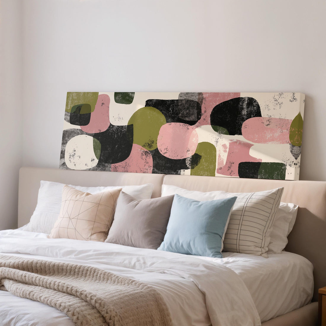a large abstract painting hanging on a wall above a bed with white sheets and pillows.