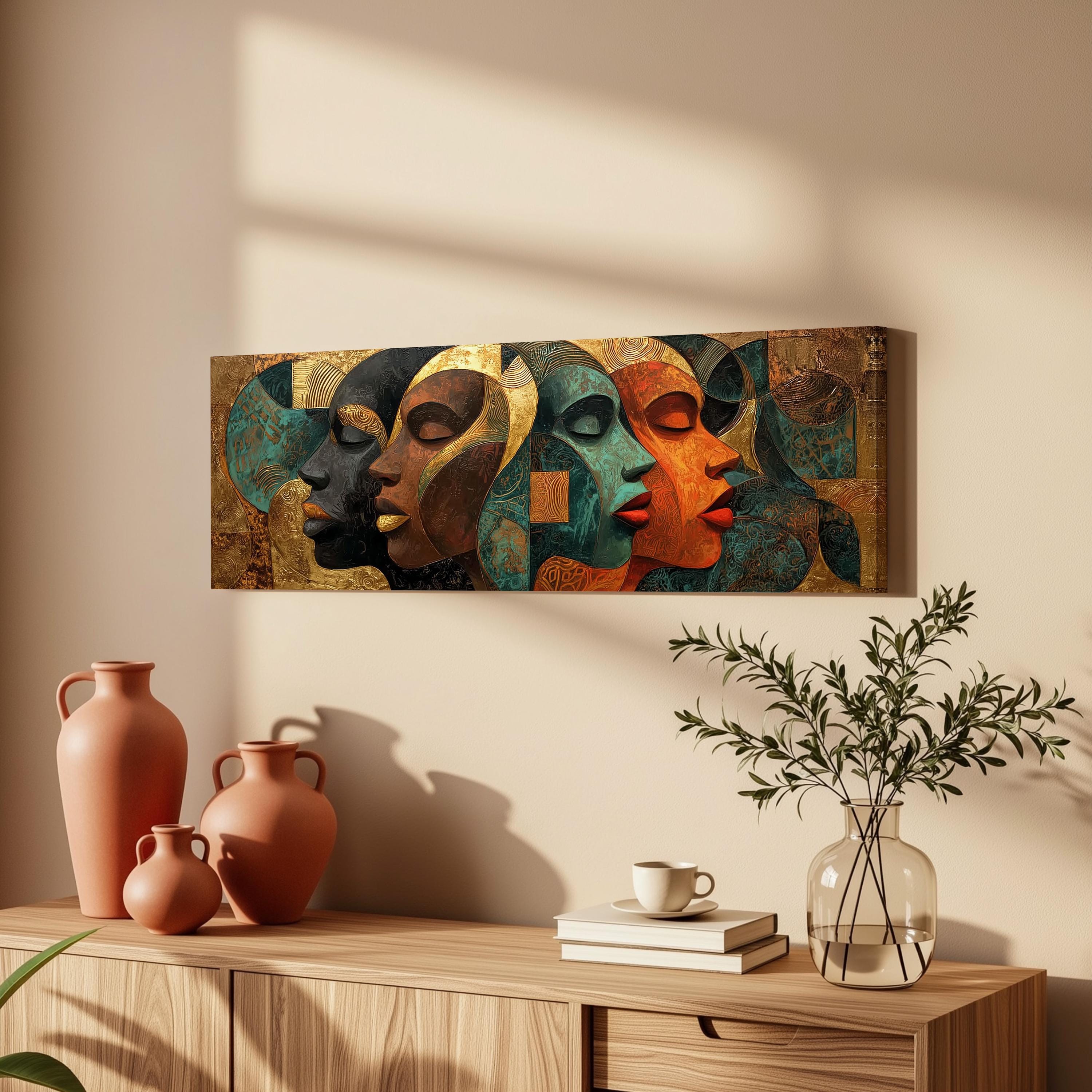 a wooden cabinet with a painting of colorful abstract faces hanging on the wall above it. The cabinet also has three orange vases, a white coffee cup, and a stack of books on top.