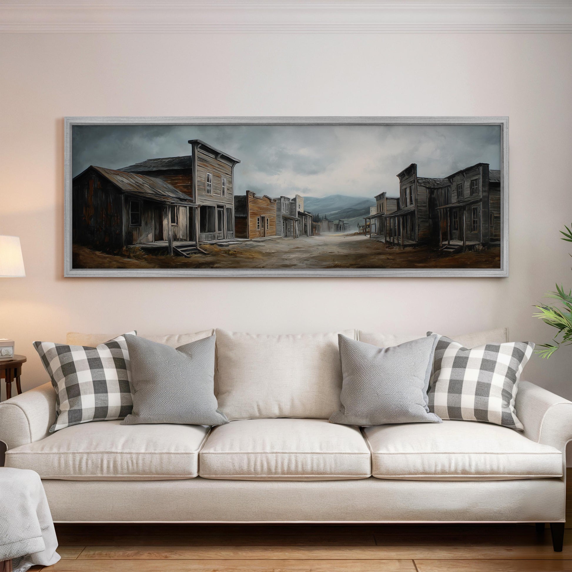 a large painting of a town scene hanging on a wall above a white sofa with gray and white patterned pillows.