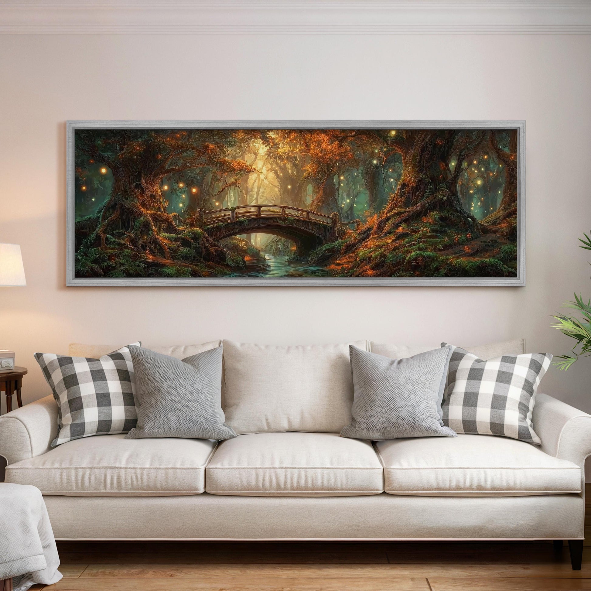 a large, framed painting of a forest scene with a bridge in the background, hanging on a wall above a white couch with patterned throw pillows.