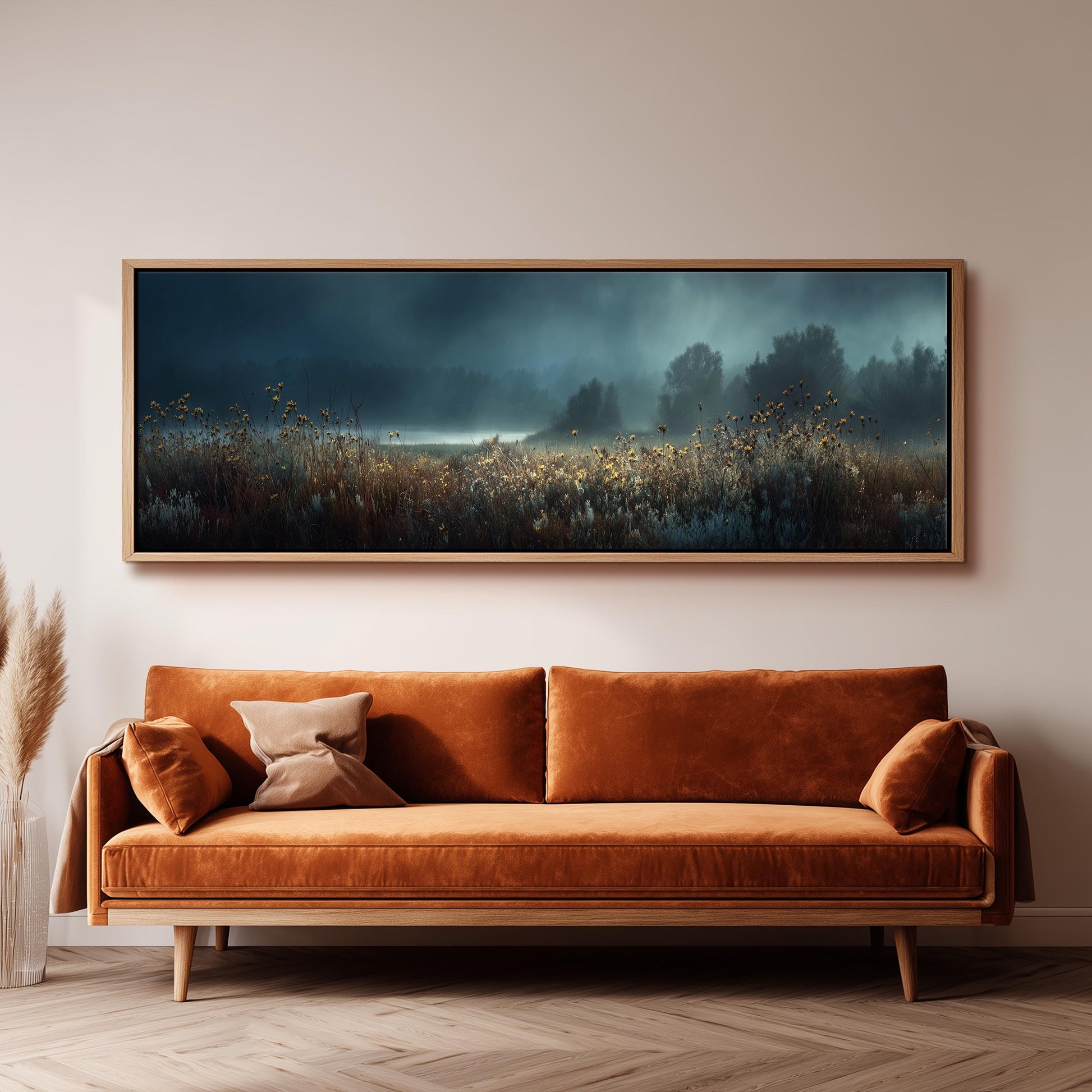a large, framed painting of a field with a misty, atmospheric background hanging on a wall above a brown sofa.