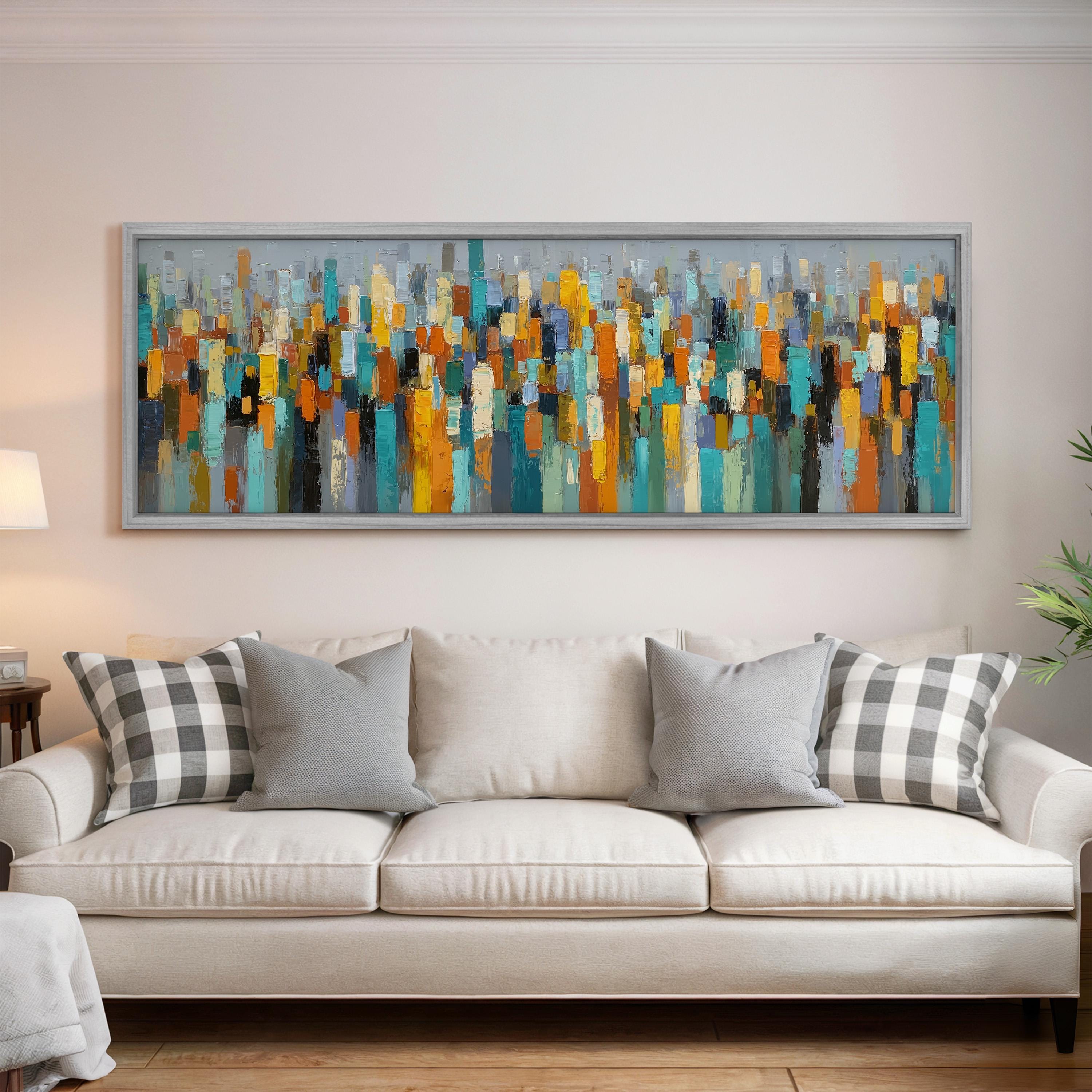 a large, colorful abstract painting hanging on a wall above a white couch with gray and black plaid throw pillows.
