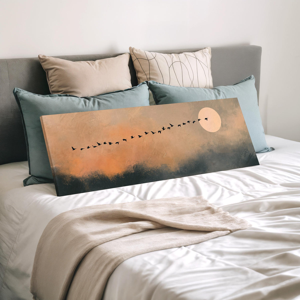 Migrating birds passing a moon at peach dusk wide panoramic canvas print laid on a bed to show its size