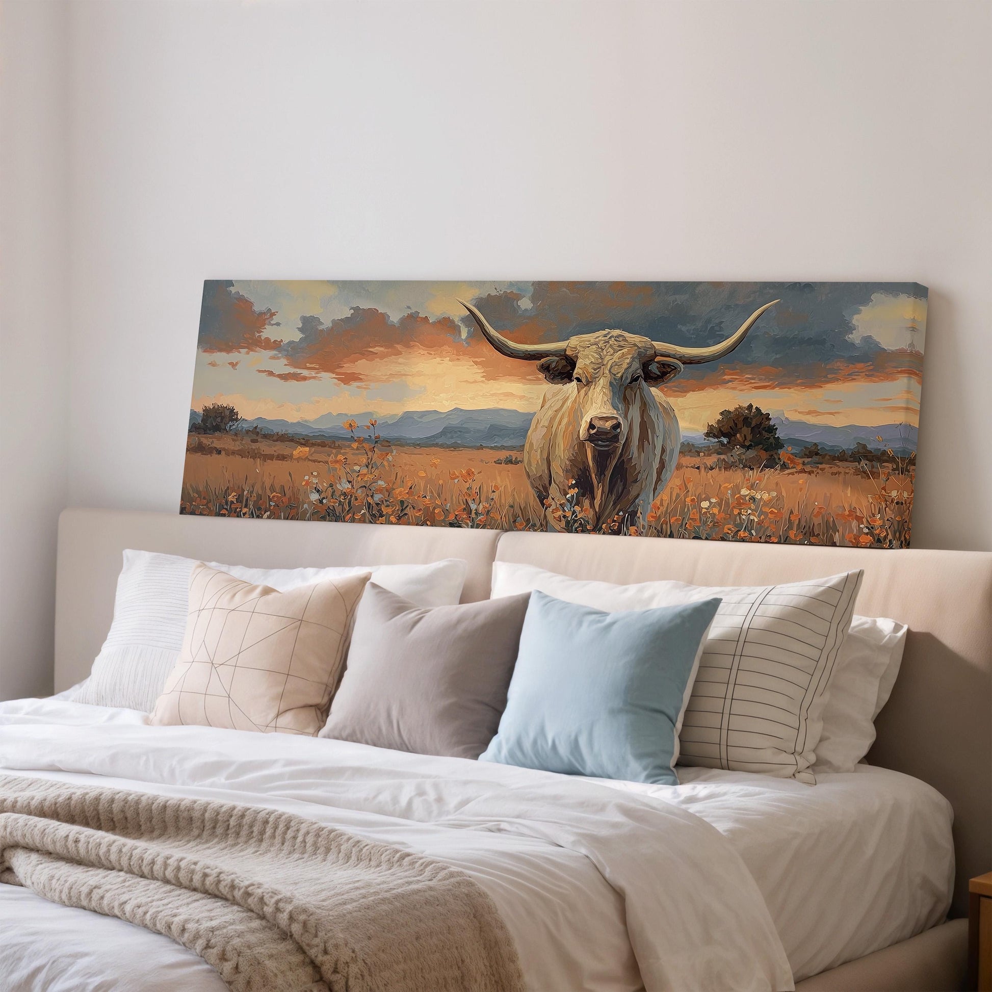a large painting of a bull with long horns, displayed on a wall above a bed with white bedding and pillows.