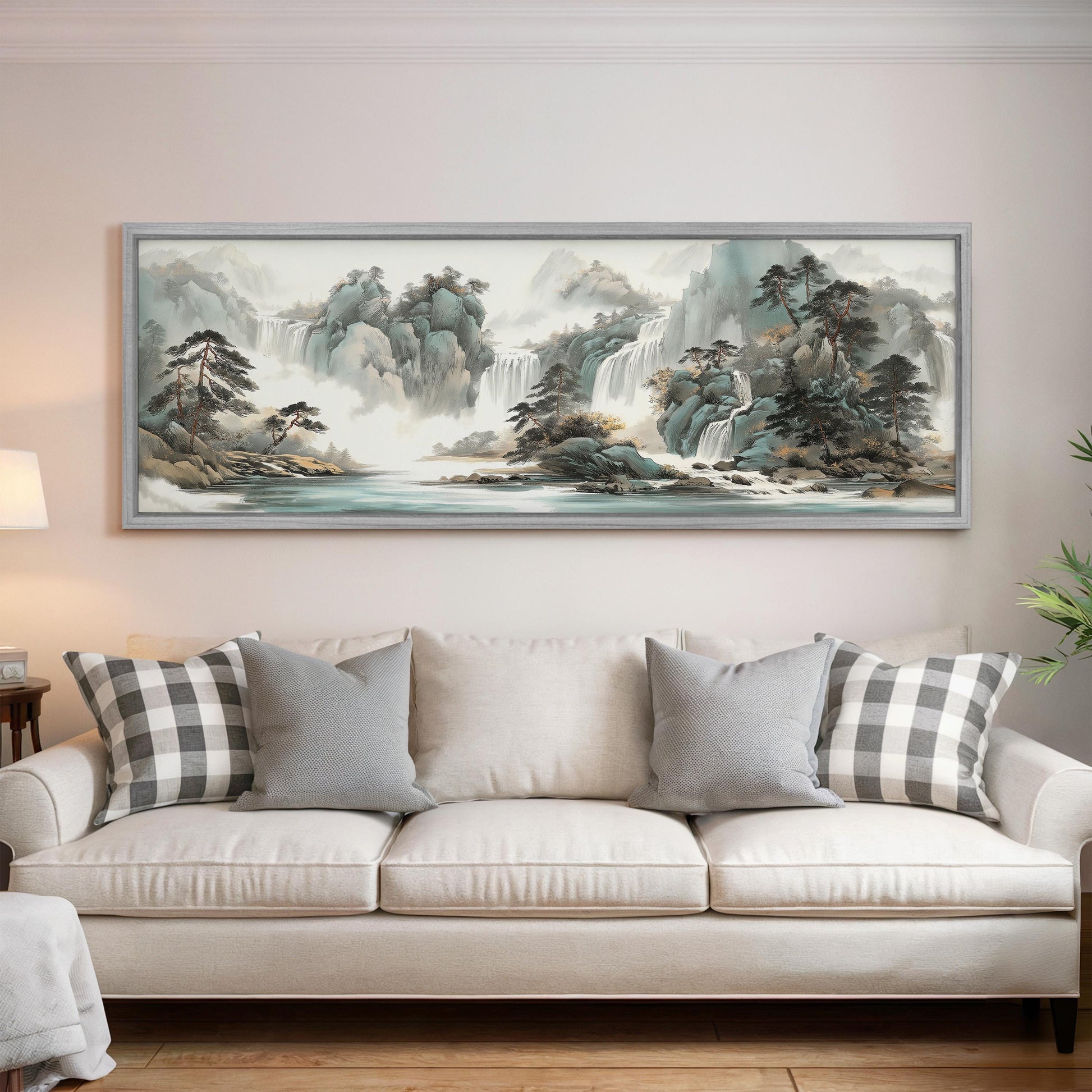 a large landscape painting hanging on a wall above a white sofa with gray and white patterned pillows.
