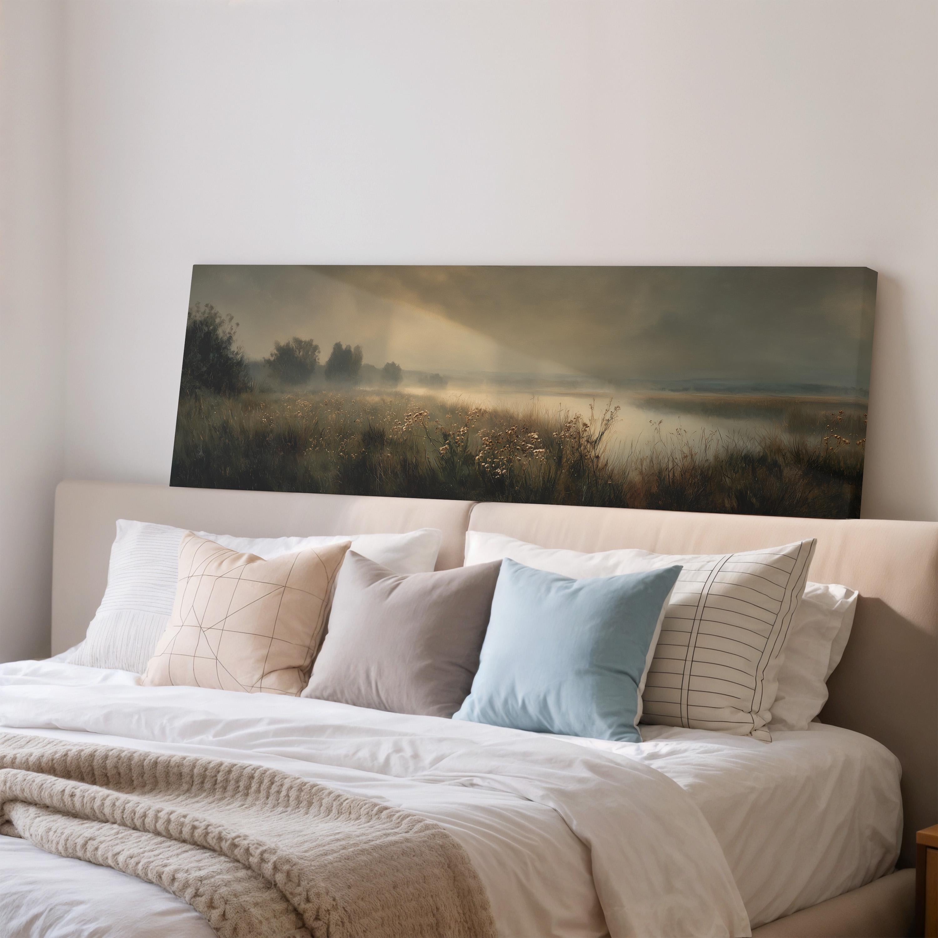a bedroom with a large bed covered in white sheets and pillows. Above the bed, there is a painting depicting a serene landscape with a field and a body of water.