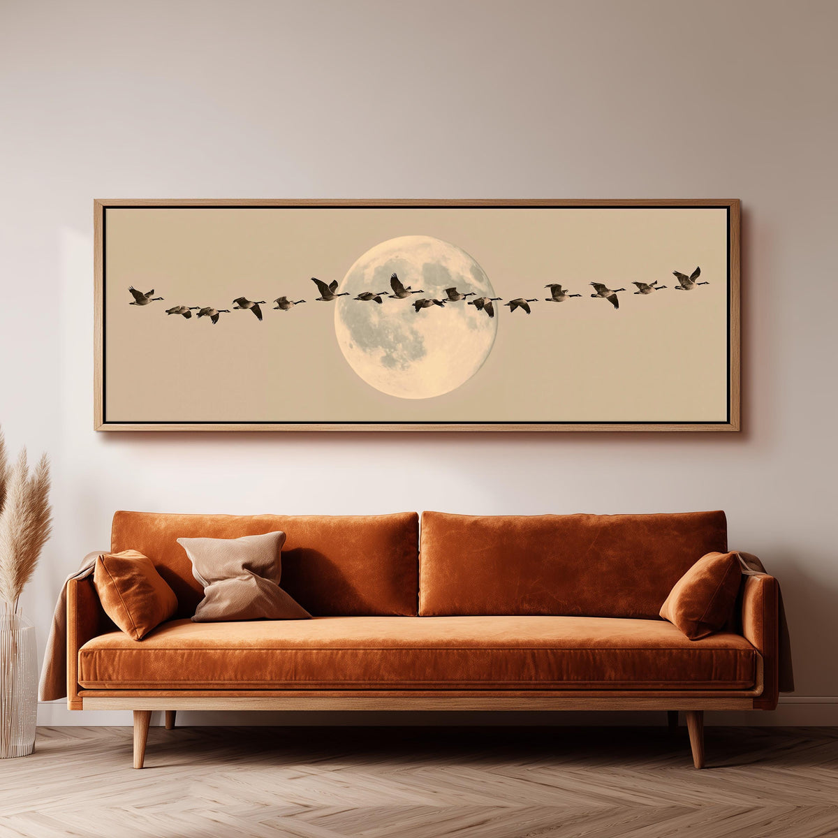 Geese flying across a pale moon on sand panoramic canvas print above a sofa in a living room