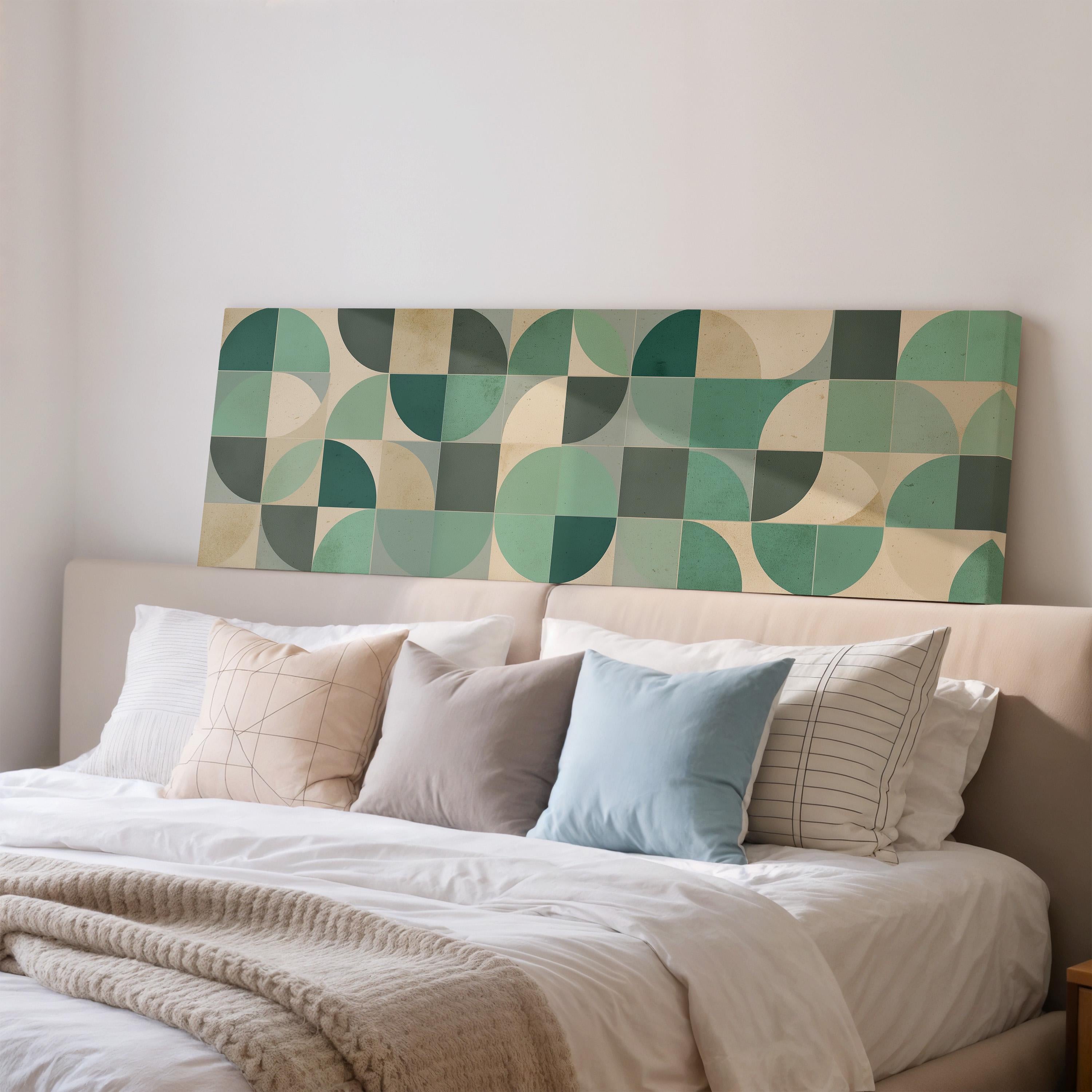 a cozy bedroom scene with a bed adorned with a white comforter and a variety of colorful pillows. Above the bed, there is a large abstract painting with a geometric pattern in shades of green and beige.