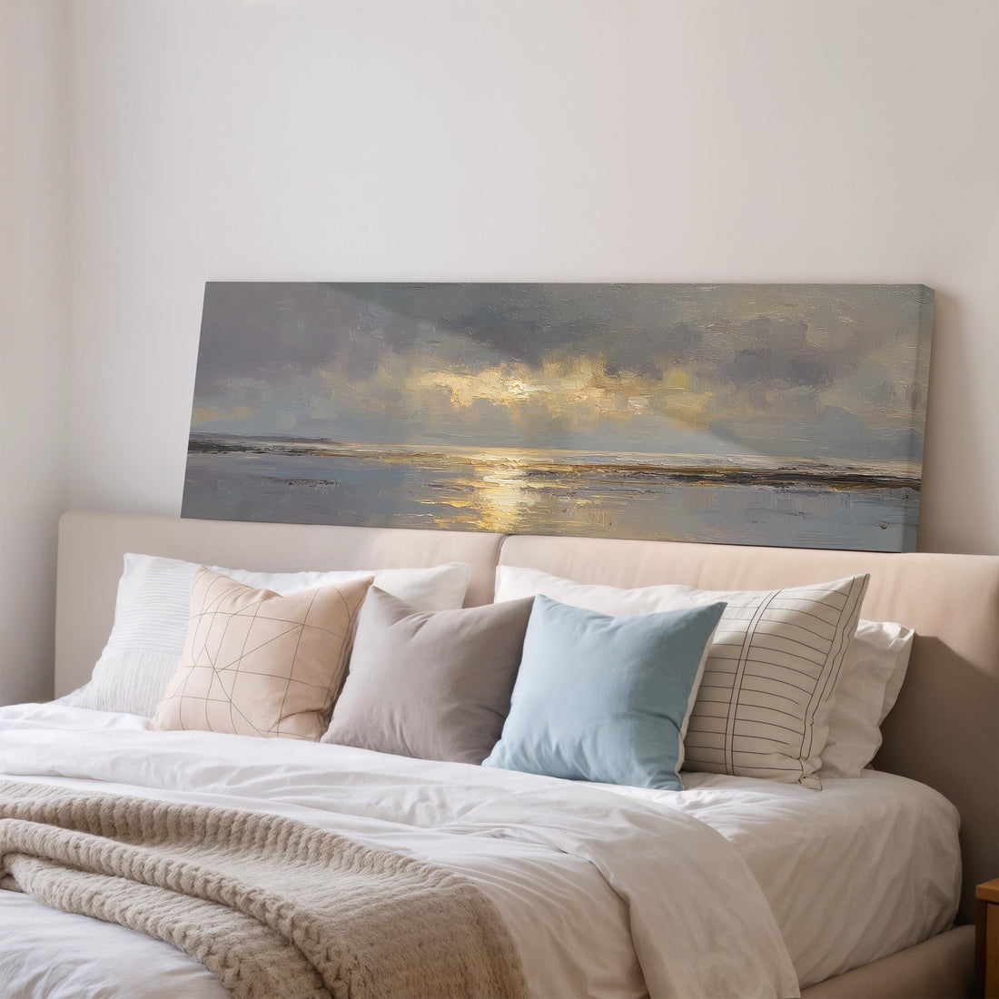 a dining room with a large painting of a serene landscape hanging on the wall above a wooden dining table with four chairs. The table is set with a bowl of fruit and a vase of flowers, creating a cozy and inviting atmosphere.