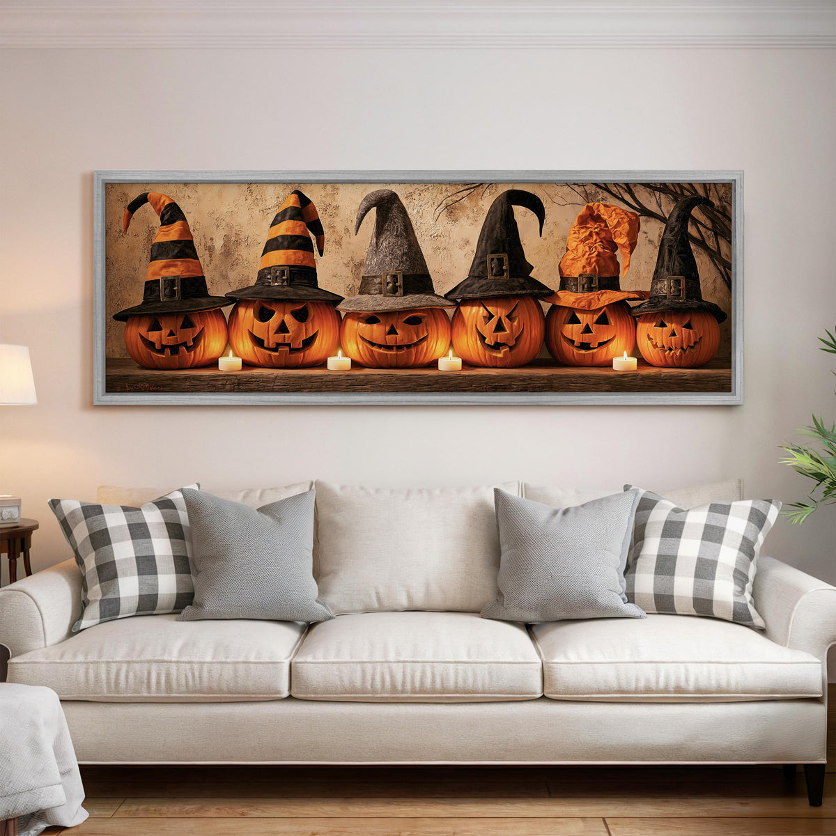 Jack-o'-lanterns wearing witch hats by candlelight panoramic canvas print above a white sofa in a bright living room