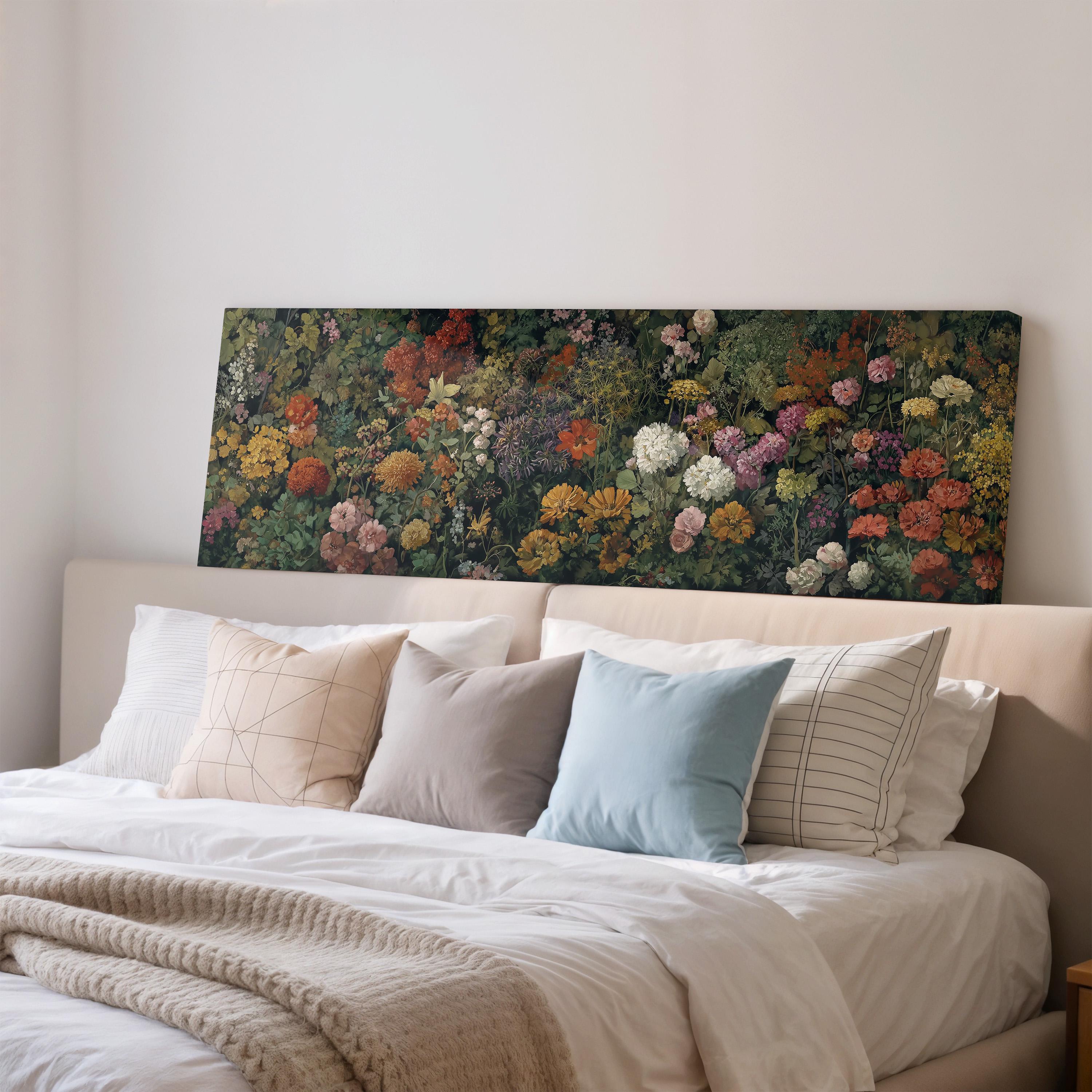 a large floral painting hanging on a wall above a bed with white pillows and a gray blanket.