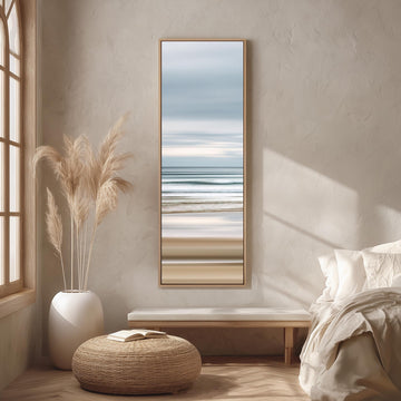 a serene bedroom scene with a large window, a painting of a beach, a white bench, a woven ottoman, and a potted plant.