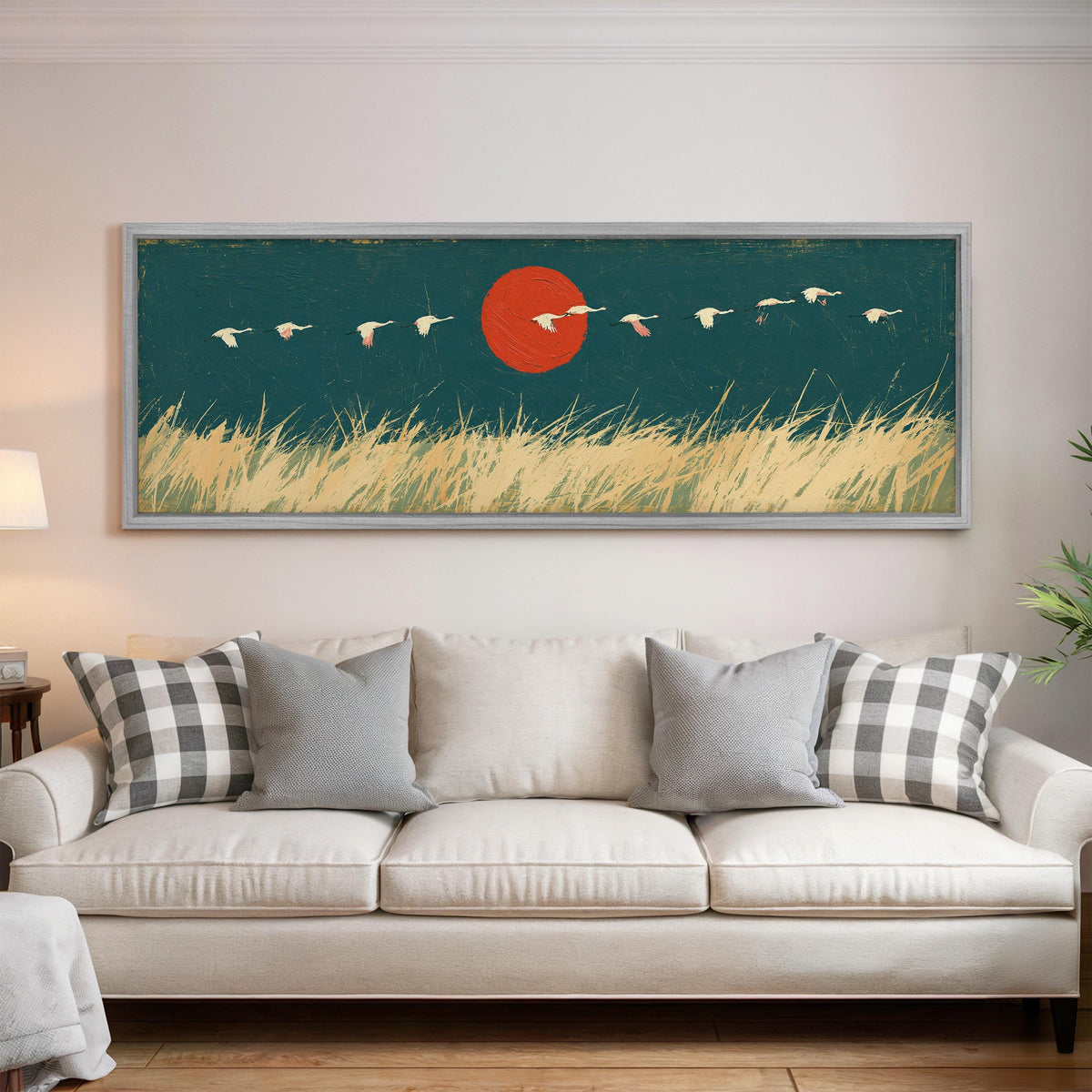 Bird flock over a prairie under a red sun panoramic canvas print above a white sofa in a bright living room