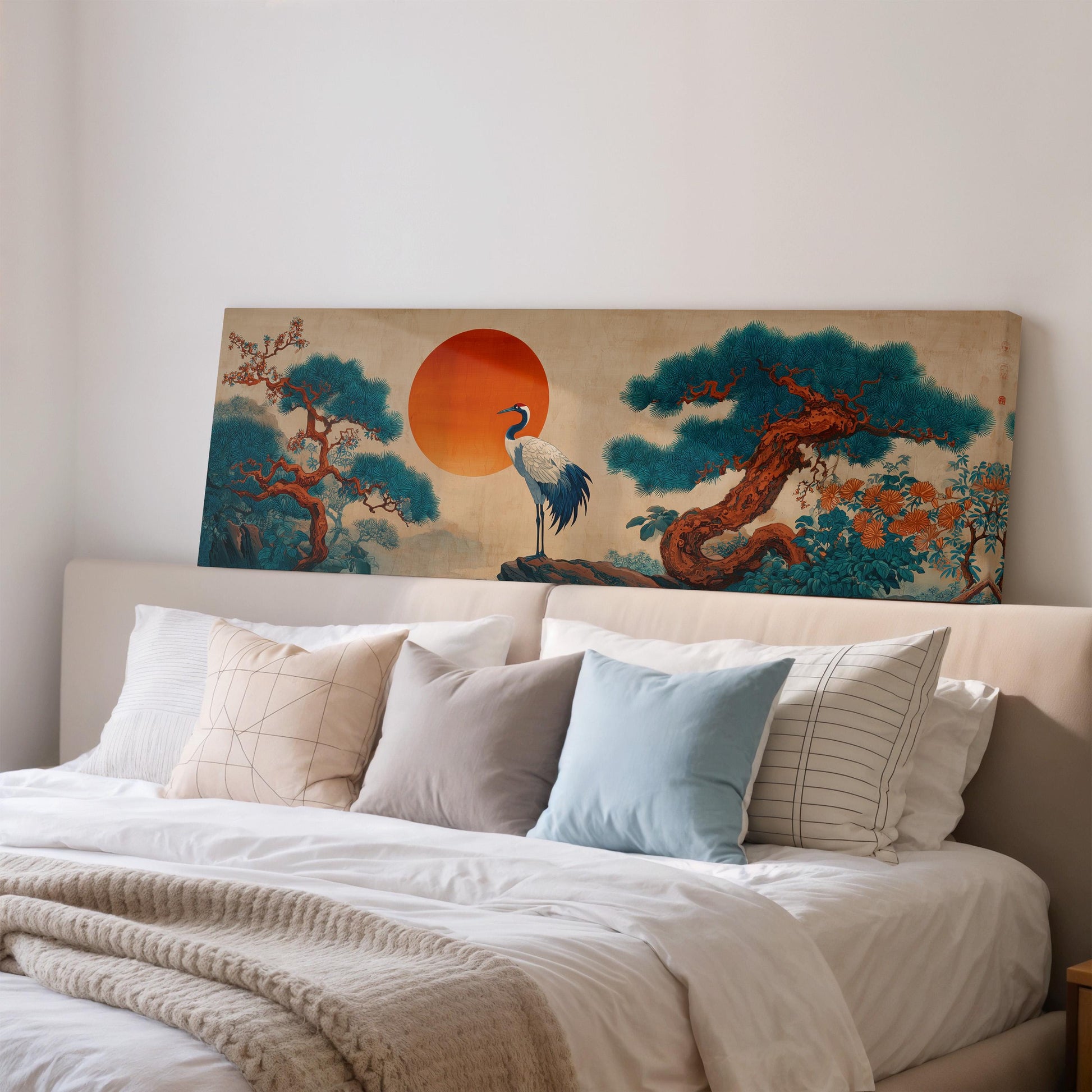 a large painting of a crane standing on a rock, with a tree and a sun in the background, mounted on a wall above a bed with white pillows and a gray blanket.