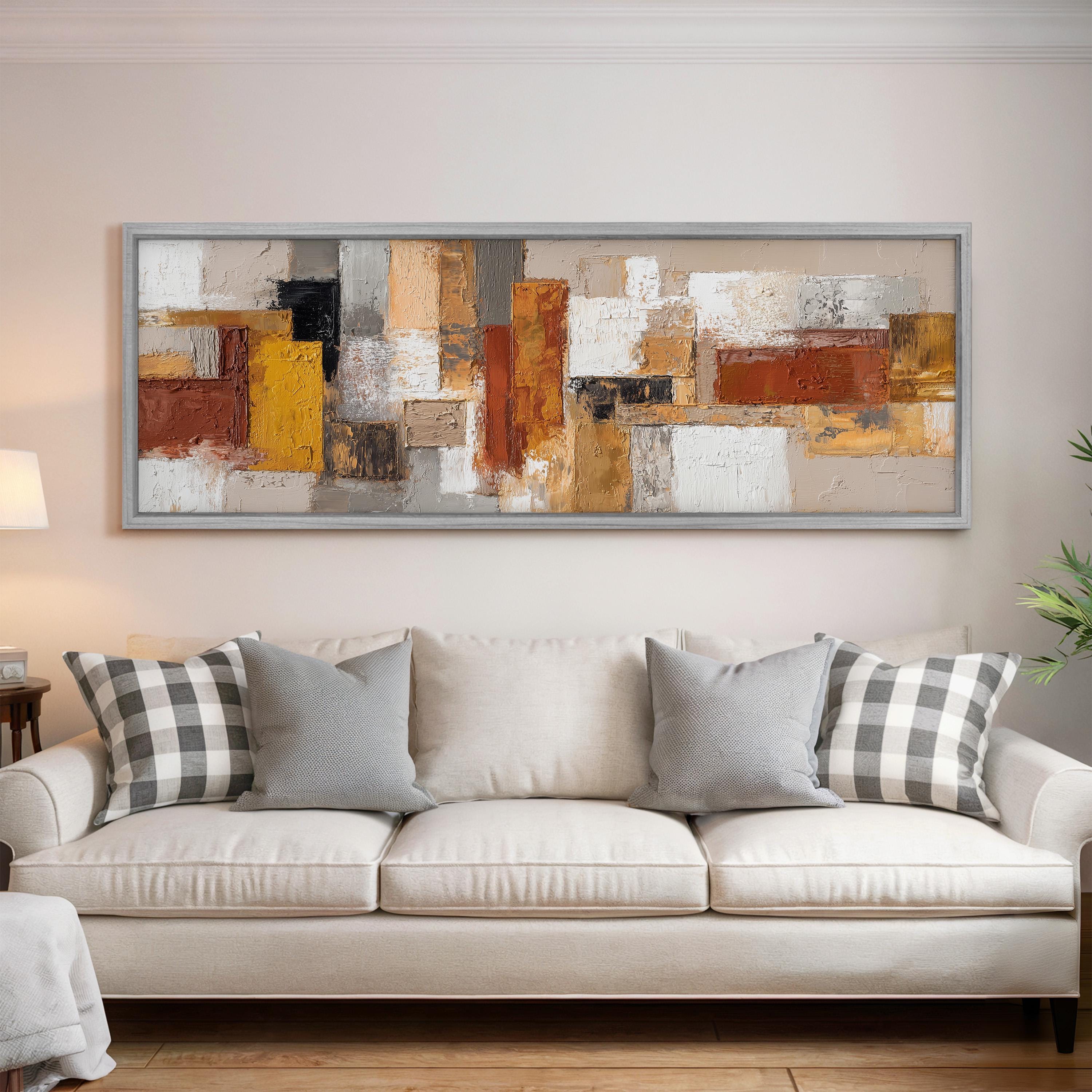 a large abstract painting hanging on a wall above a white sofa with gray and white plaid throw pillows.