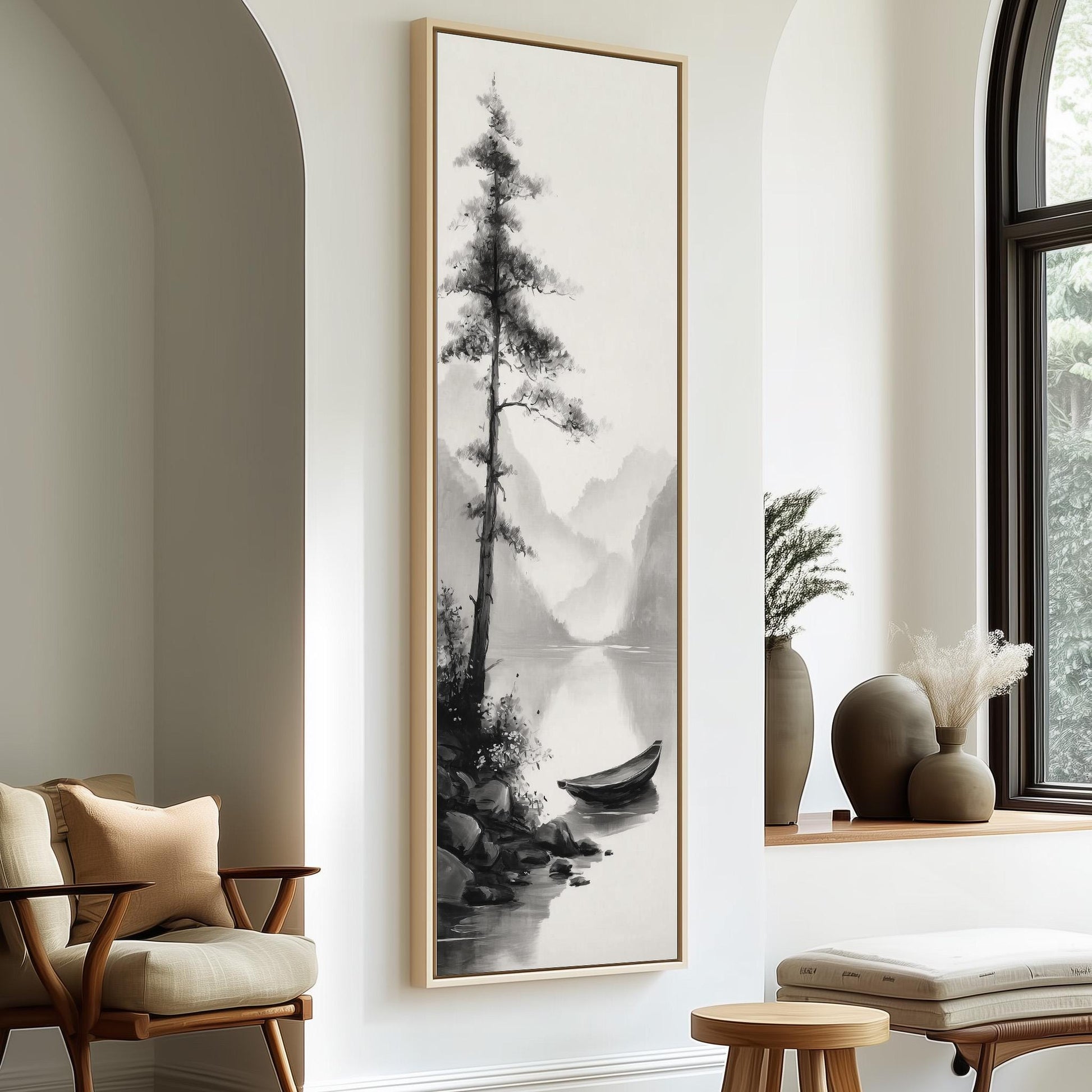 a large black and white painting of a tree and a boat on a lake, hanging on a white wall in a room with a window and a wooden chair.