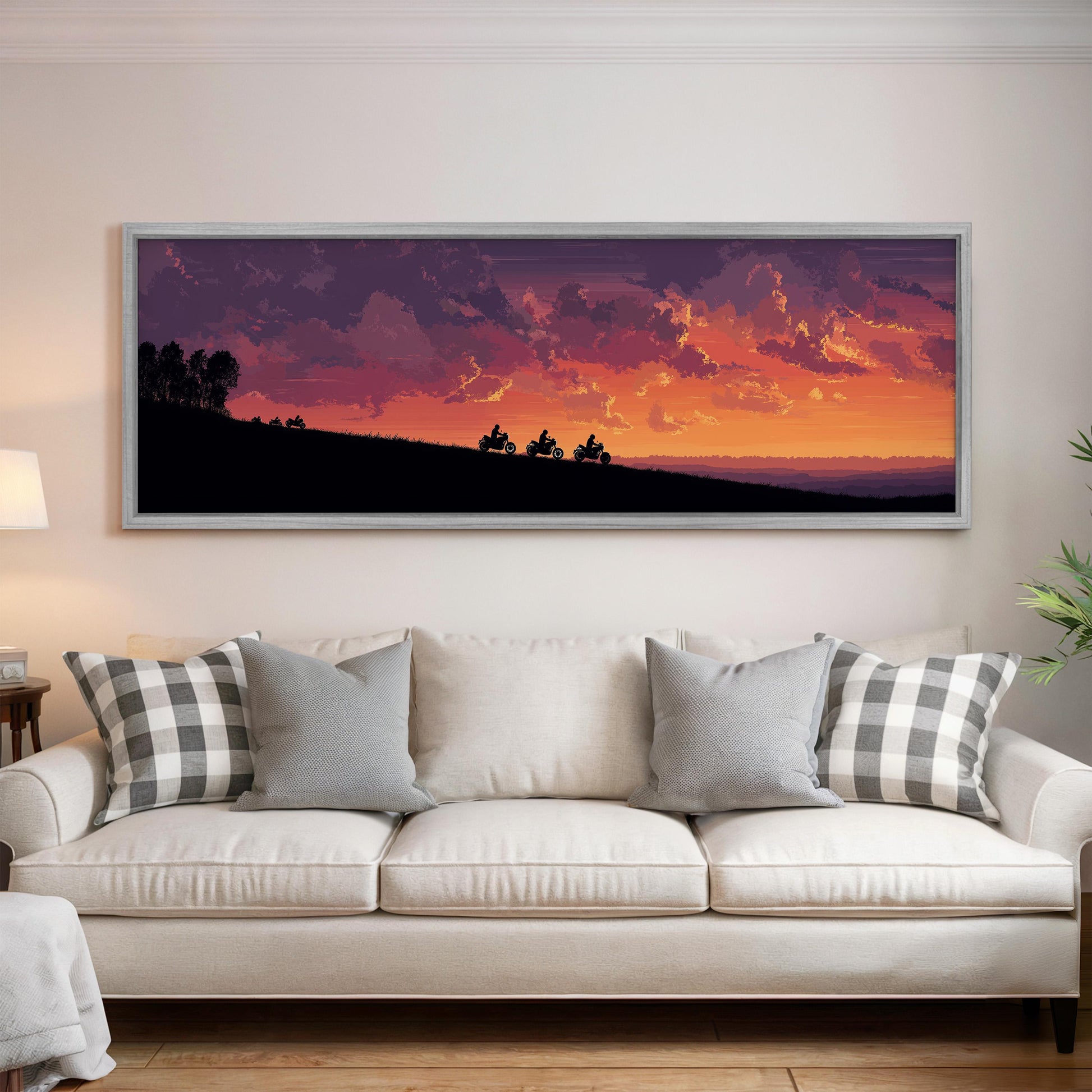 a large, framed painting of a sunset landscape hanging on a wall above a white couch with gray and white patterned pillows.