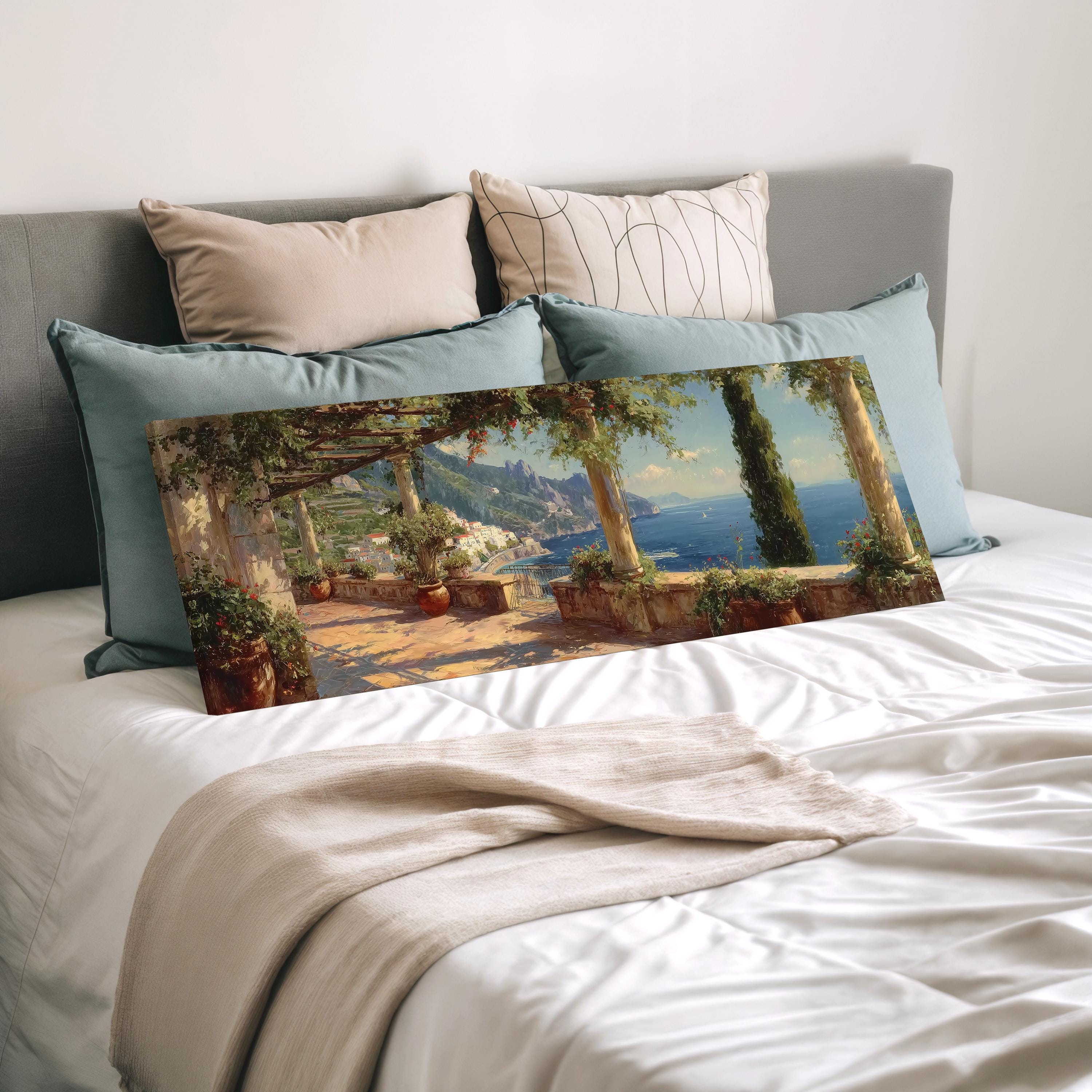 a large painting of a scenic outdoor landscape, with a view of a mountain and a body of water, displayed on a bed with pillows.