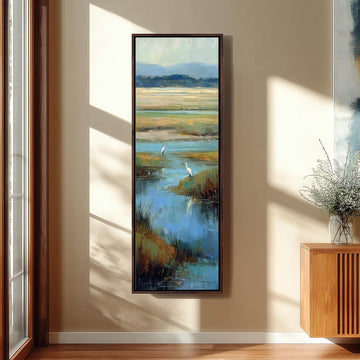 a large framed painting hanging on a wall, depicting a serene landscape with a body of water and two white birds.