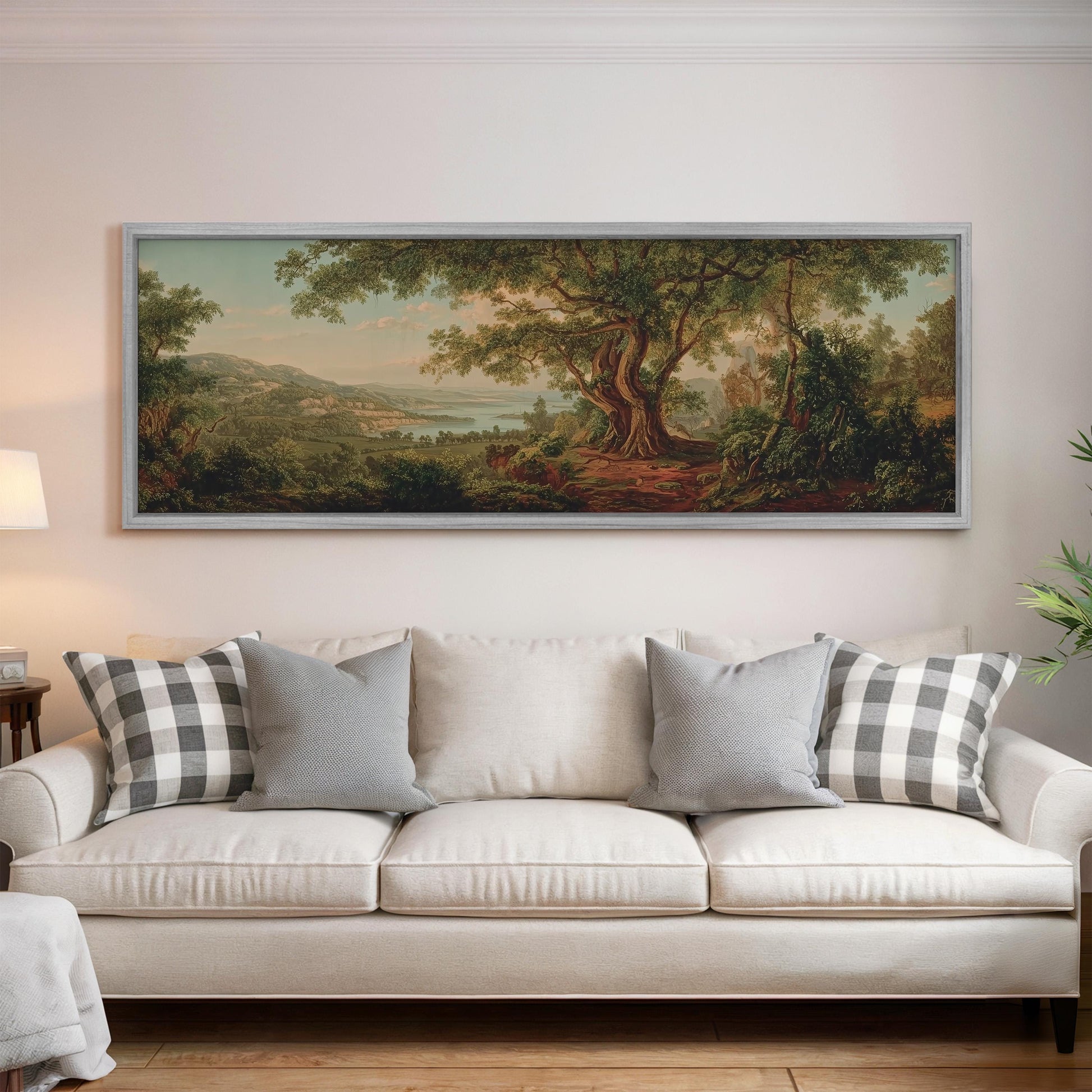 a large landscape painting hanging on a wall above a white sofa with gray and white plaid throw pillows.