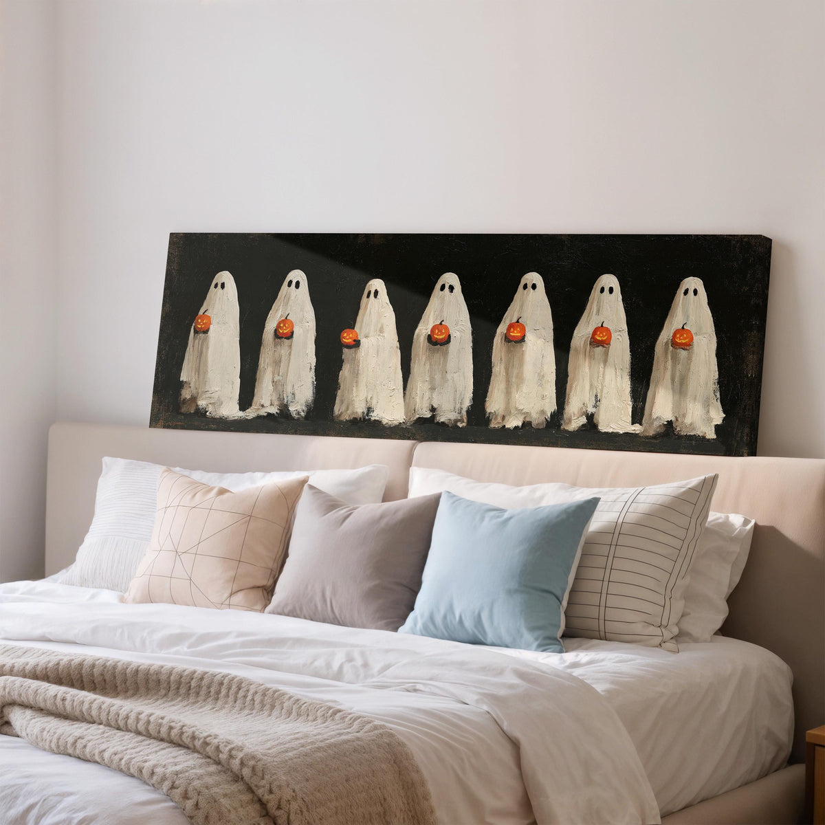 Row of ghosts holding pumpkins wide panoramic canvas print above a bed in a bedroom