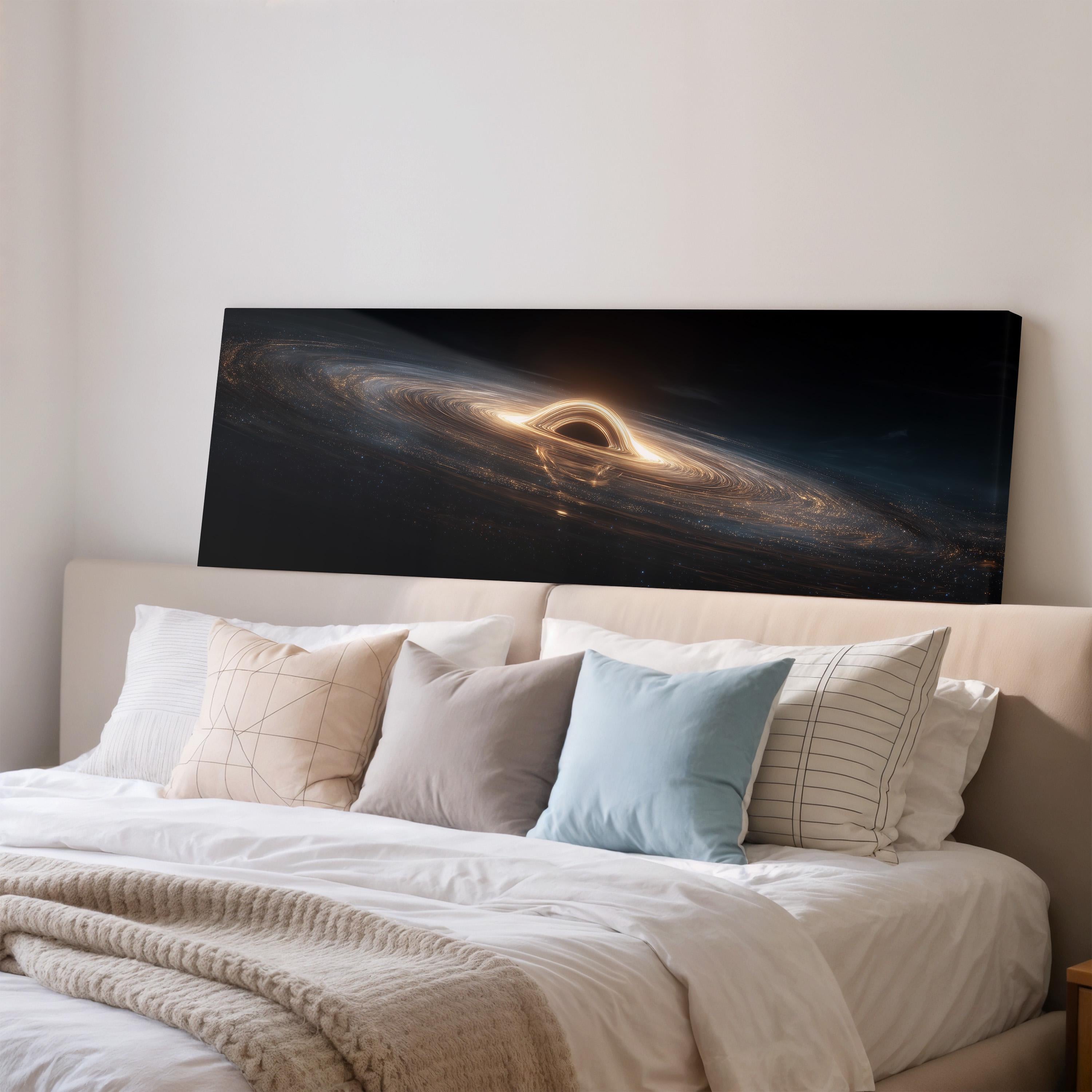 a large black canvas print of a spiral galaxy with a bright black hole at its center, hanging above a bed with white pillows and a gray blanket.