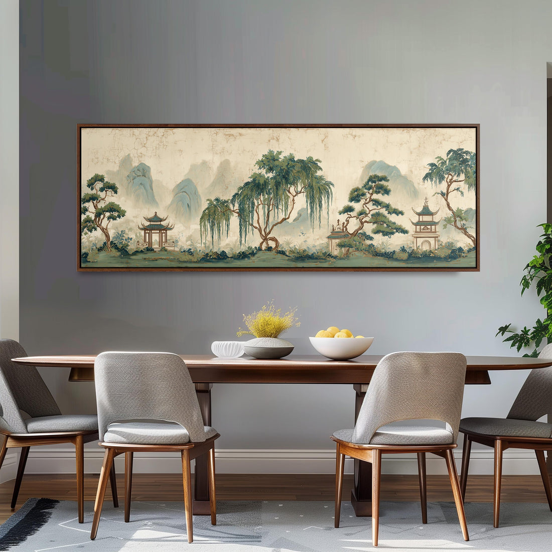 a large, framed painting of a serene landscape with mountains, trees, and pagodas hanging on a wall above a brown sofa.