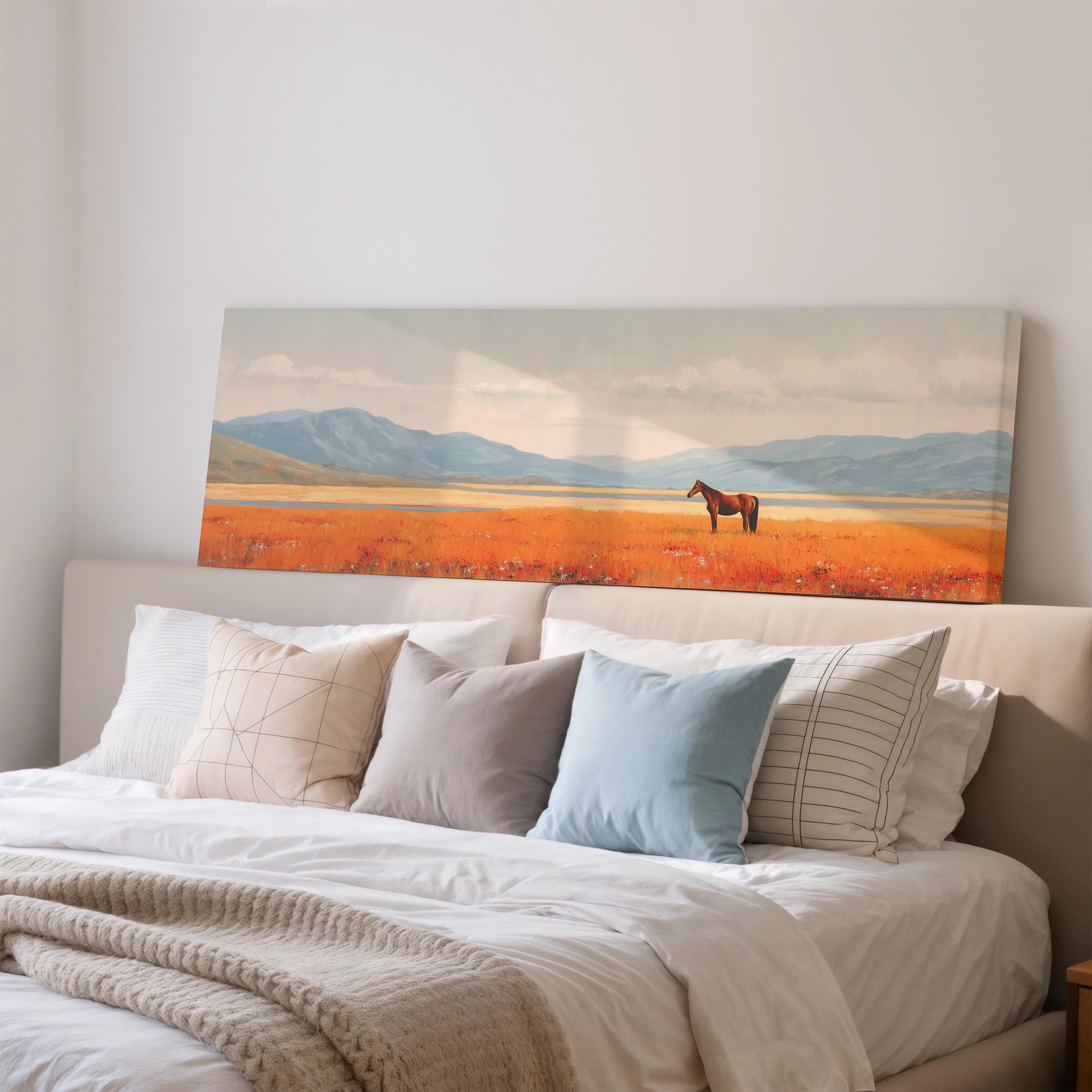 a large painting of a horse in a field, hanging on a wall above a bed with white pillows and a gray blanket.