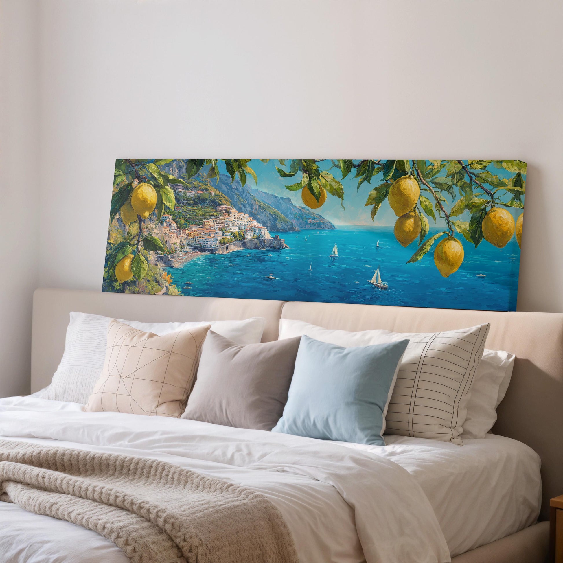a large painting of a coastal town with a picturesque view of the sea, hanging above a bed with white pillows and a gray blanket.