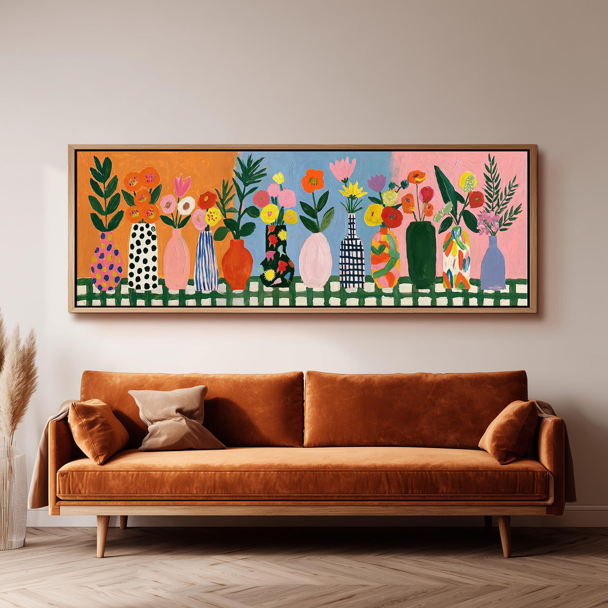 Folk art flower vases on orange and blue panoramic canvas print above a sofa in a living room