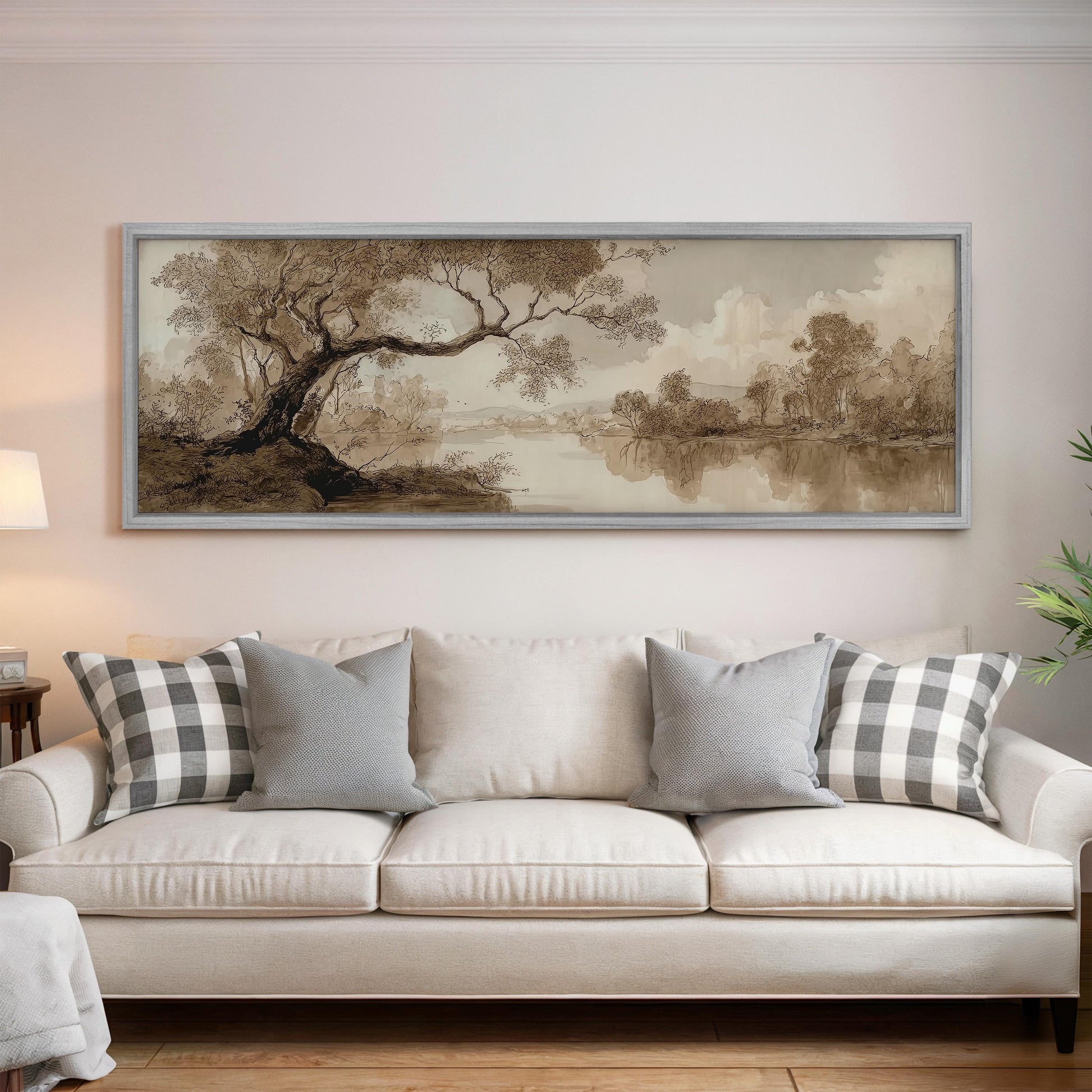 a large, framed painting of a landscape hanging on a wall above a white sofa with gray and white plaid throw pillows.