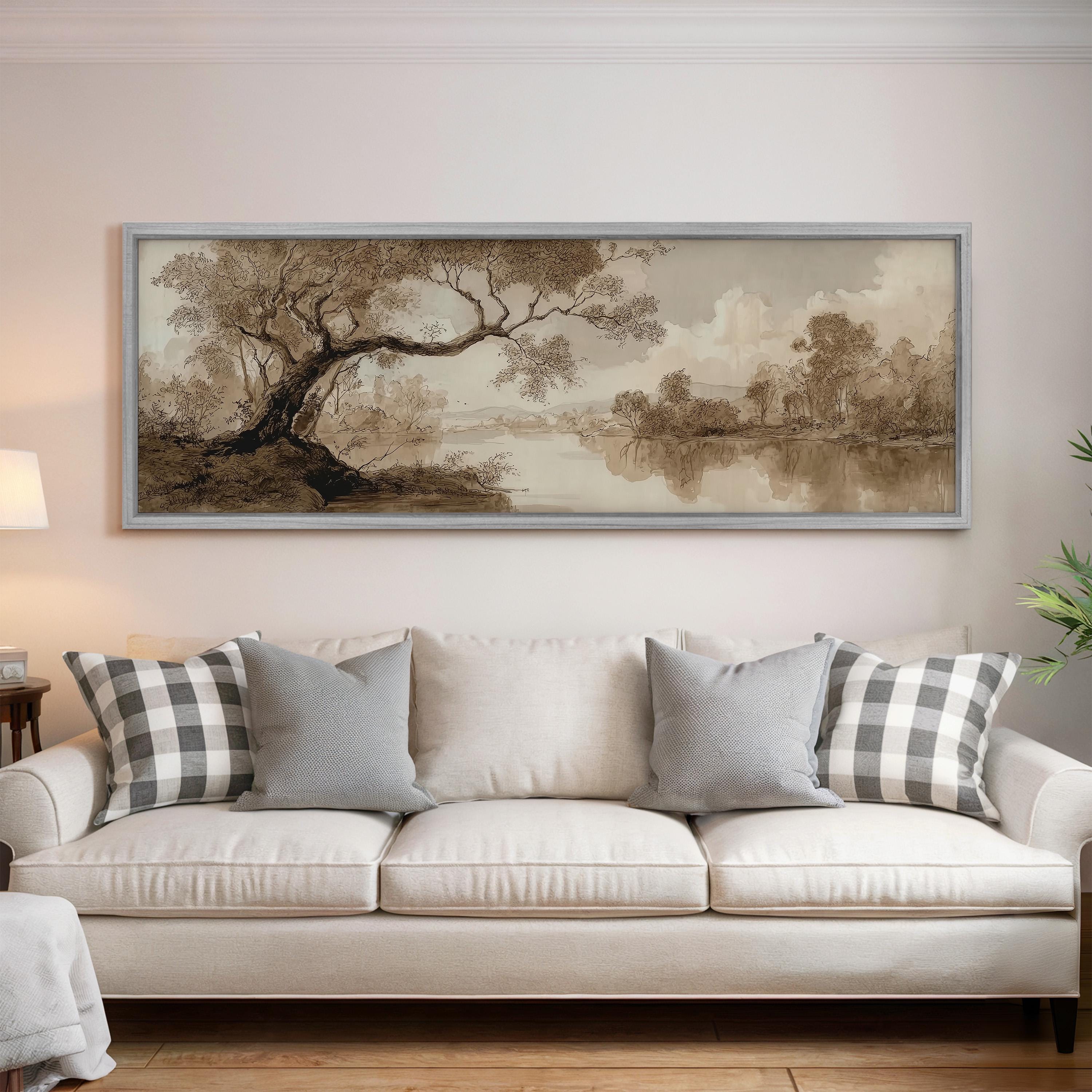 a large, framed painting of a landscape hanging on a wall above a white sofa with gray and white plaid throw pillows.