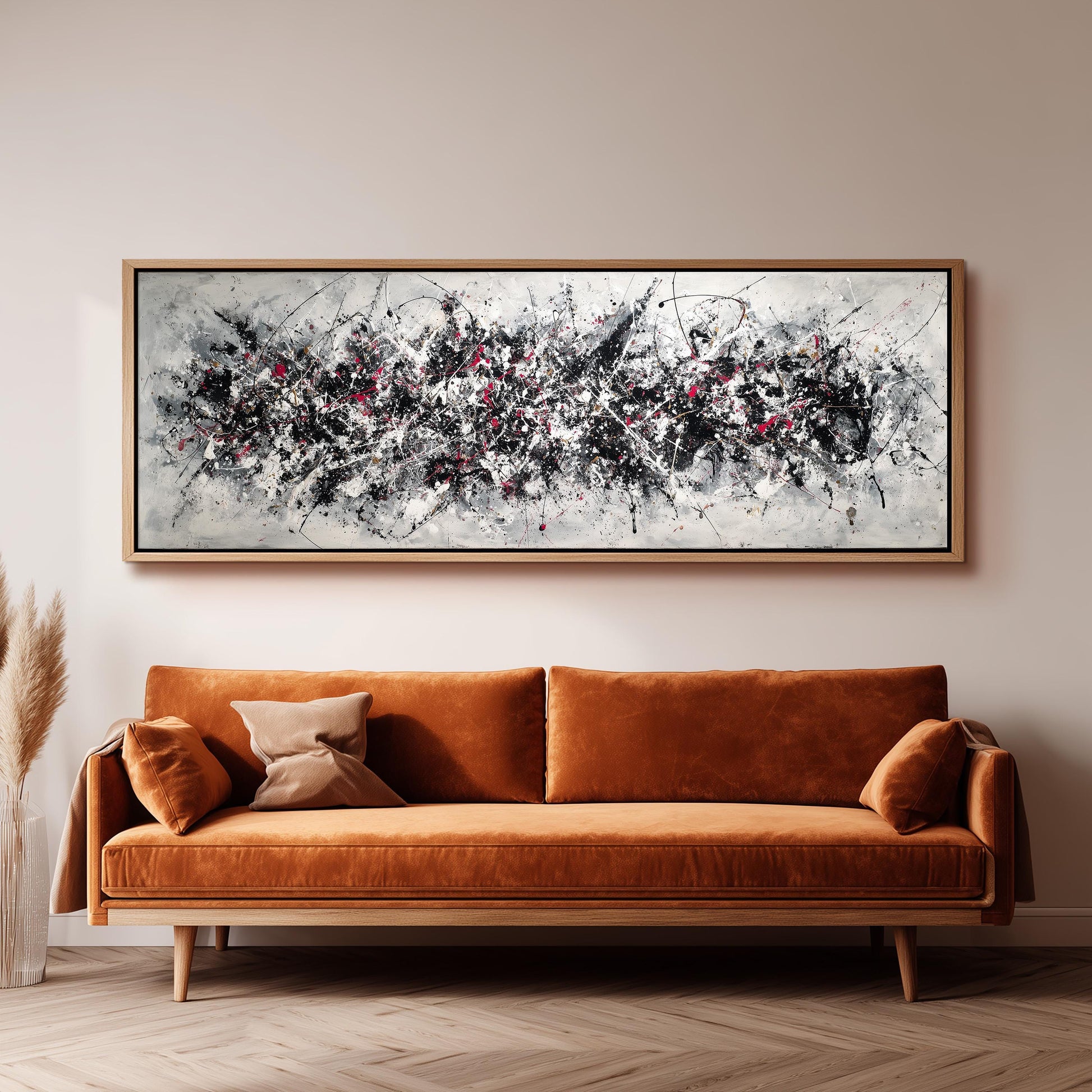 a large abstract painting hanging on a wall above a brown sofa with orange cushions.
