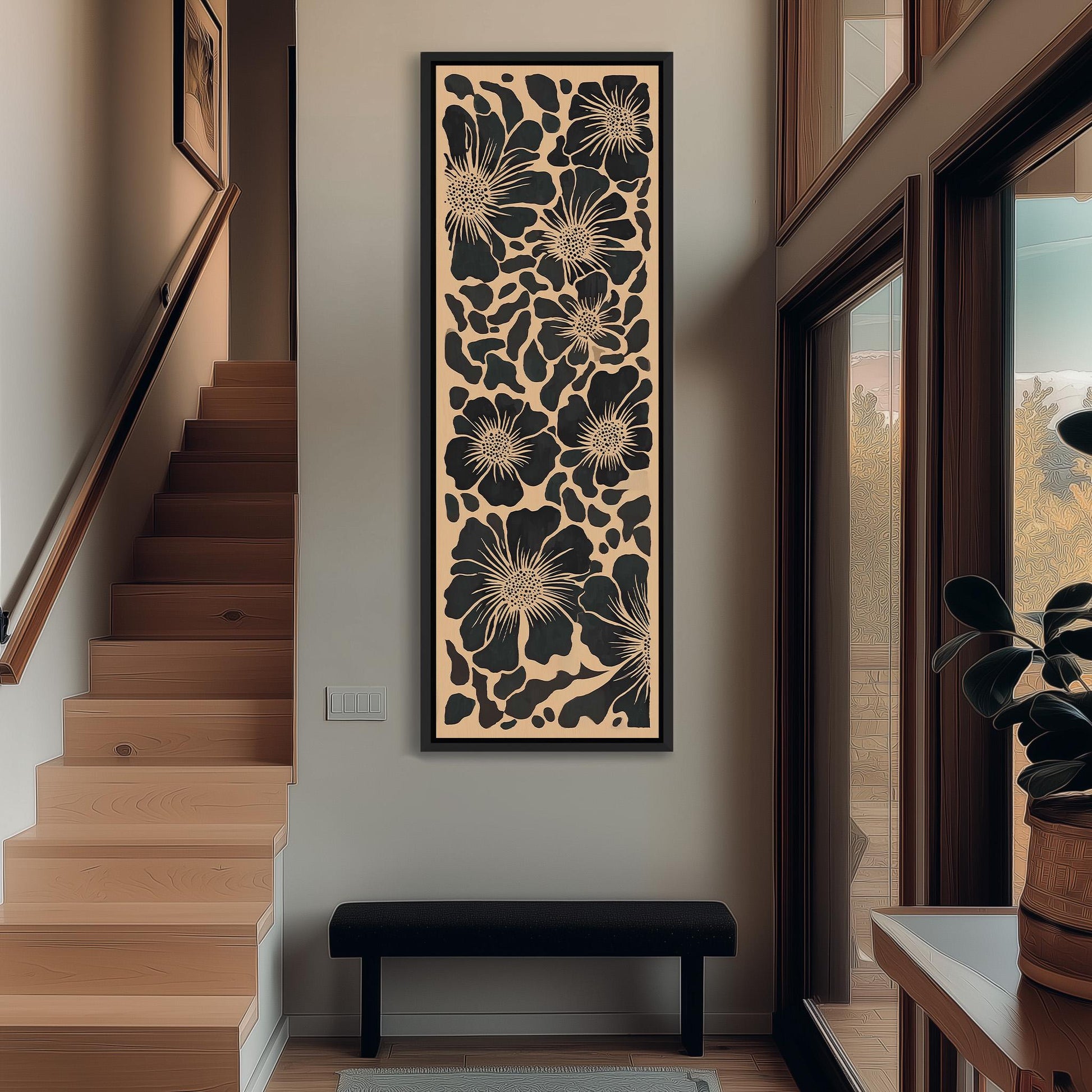 a modern interior design with a large floral artwork hanging on the wall above a black bench. The artwork is a vertical piece with a floral pattern in black and white. The room has wooden stairs leading up to a door, and there is a window with a view of trees outside.
