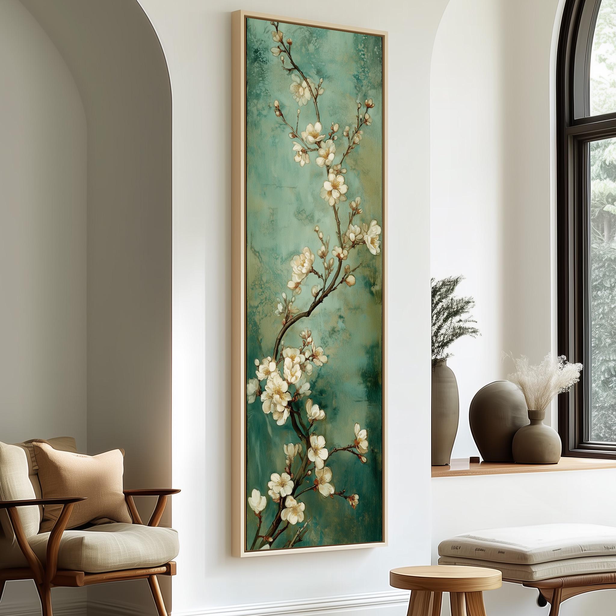 a large framed painting of white flowers on a green background hanging on a wall in a room with a wooden chair, a small table, and a window.