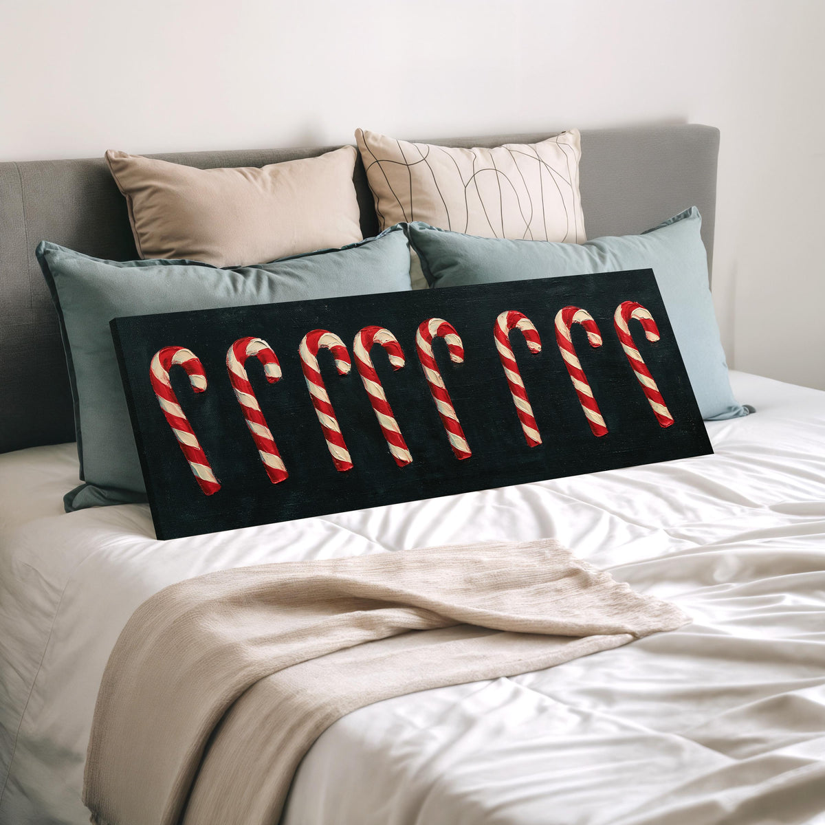 Row of candy canes on black wide panoramic canvas print laid on a bed to show its size