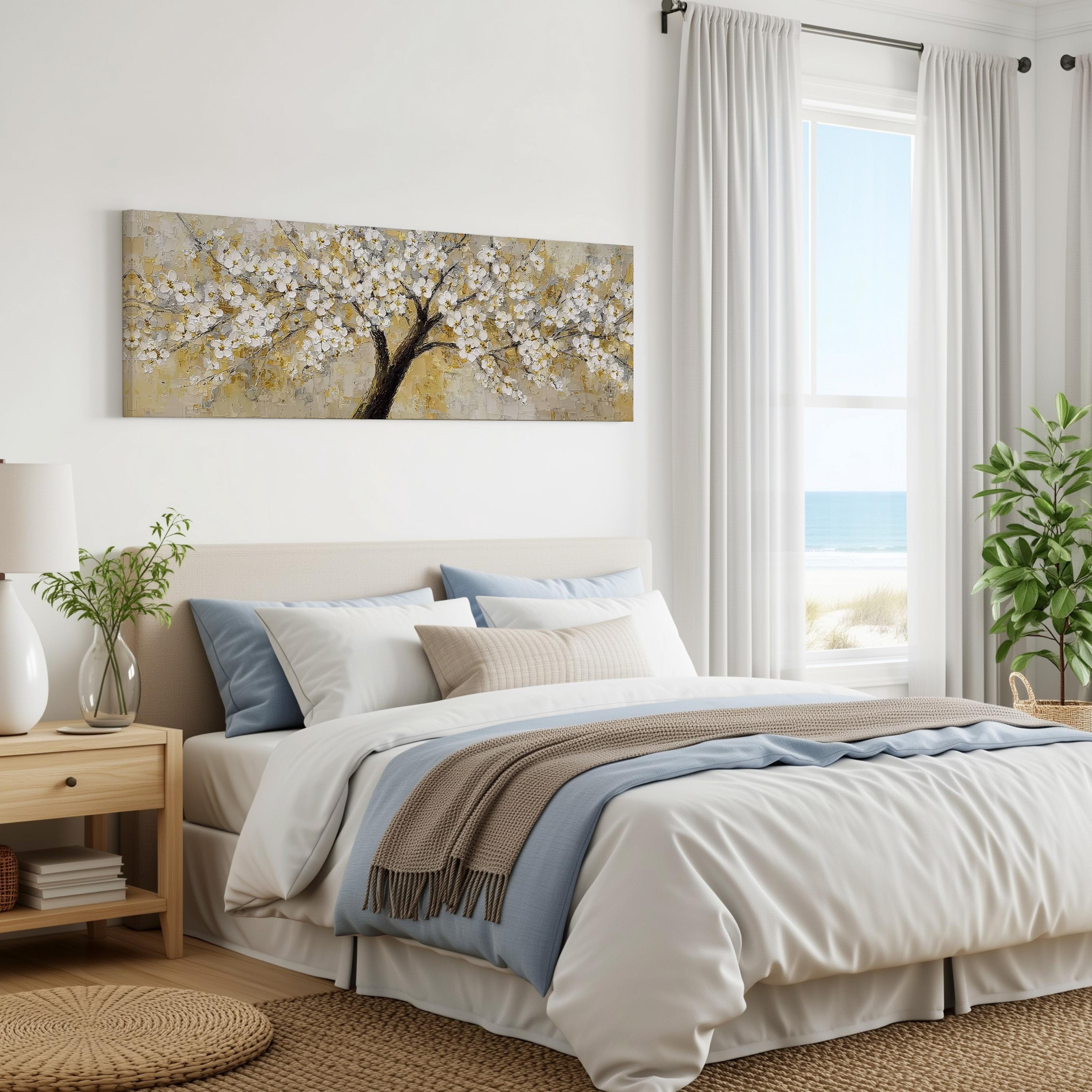 a serene bedroom with a large bed, a nightstand, and a painting of a tree with white flowers on the wall. The room has a calming and peaceful atmosphere, with natural light coming in through the window and a view of the ocean.