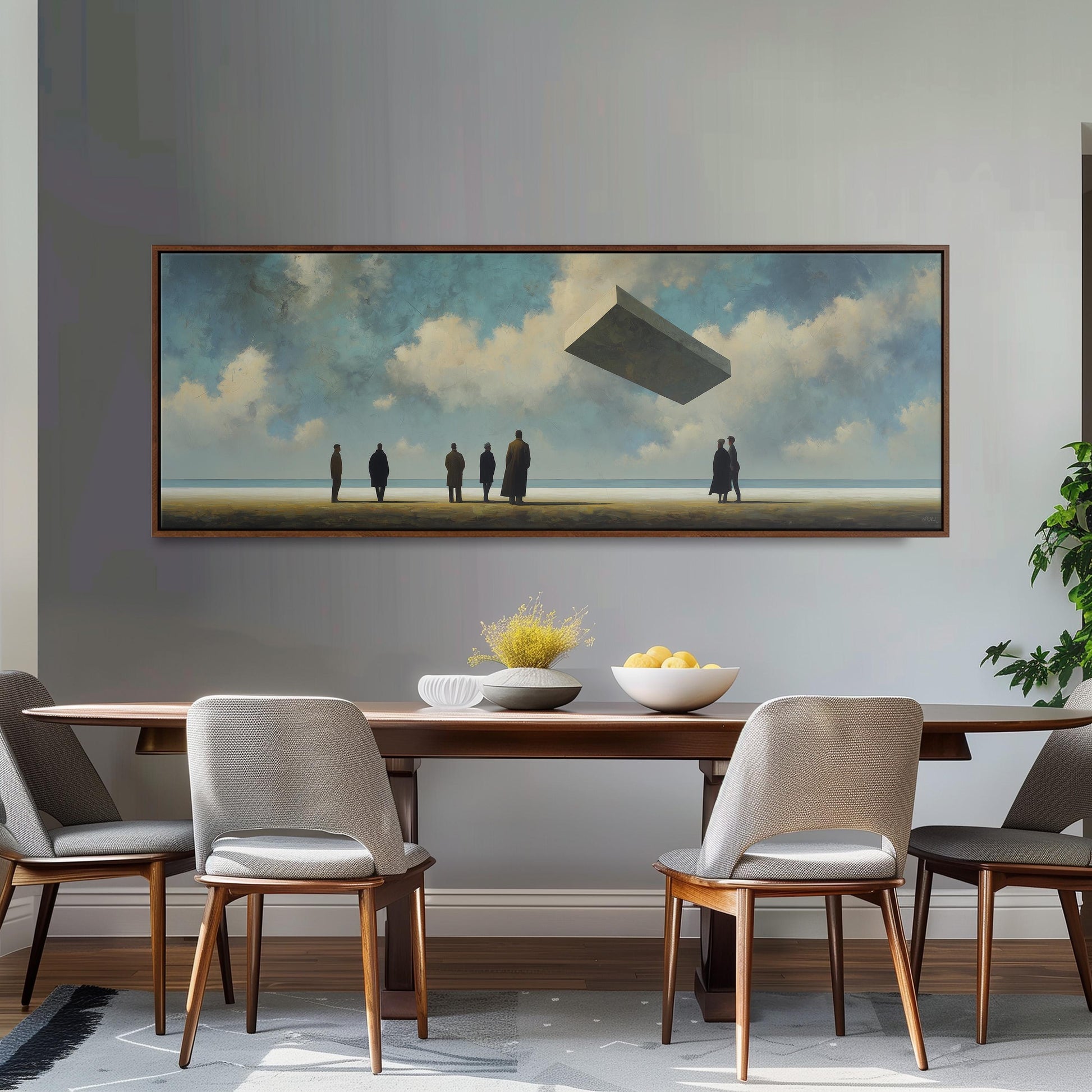 a large painting of a group of people standing on a beach, with a floating object in the sky above them. The painting is hung on a wall above a wooden dining table with four chairs.