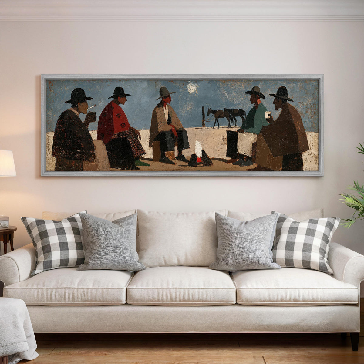 Cowboys gathered around a campfire panoramic canvas print above a white sofa in a bright living room