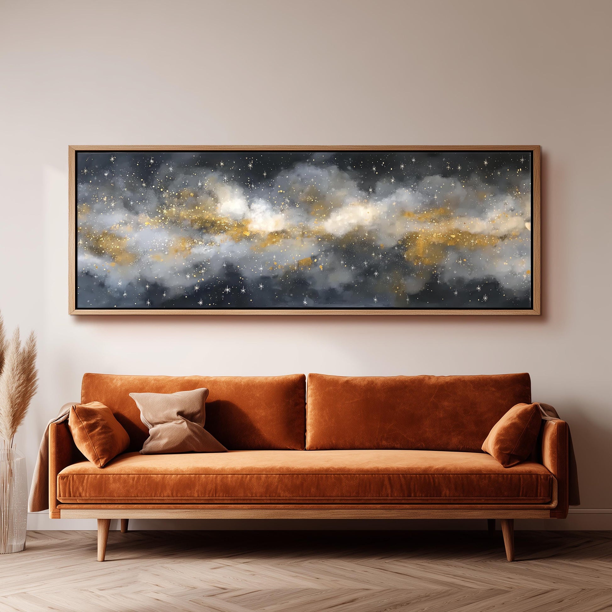 a large, framed painting of a starry night sky hanging on a wall above a brown sofa with orange cushions.