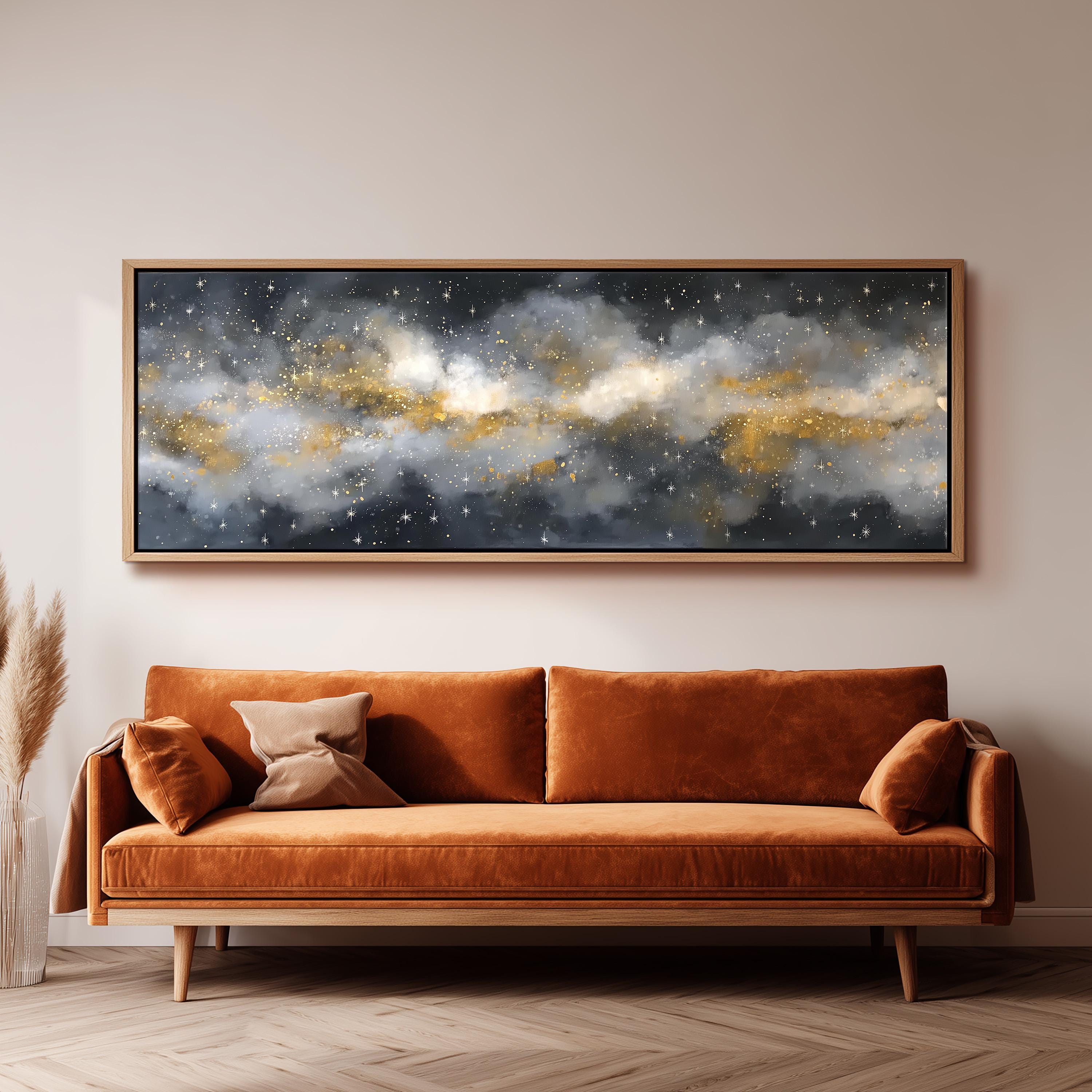 a large, framed painting of a starry night sky hanging on a wall above a brown sofa with orange cushions.