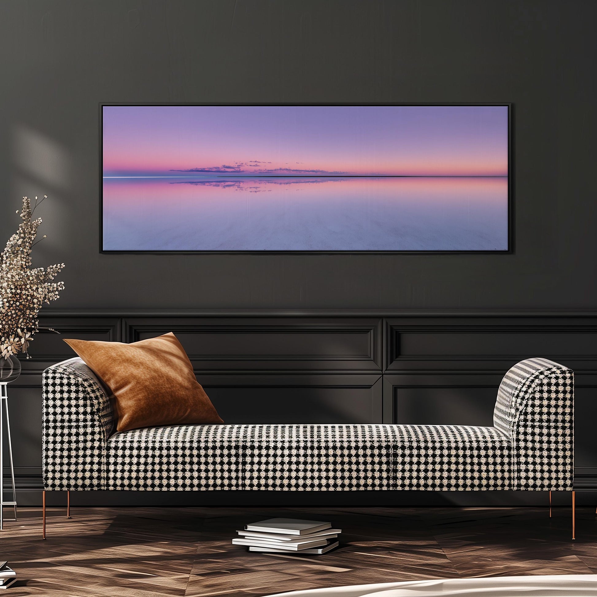 a checkered sofa with a brown throw pillow, set against a dark wall with a large framed landscape photograph hanging above it.