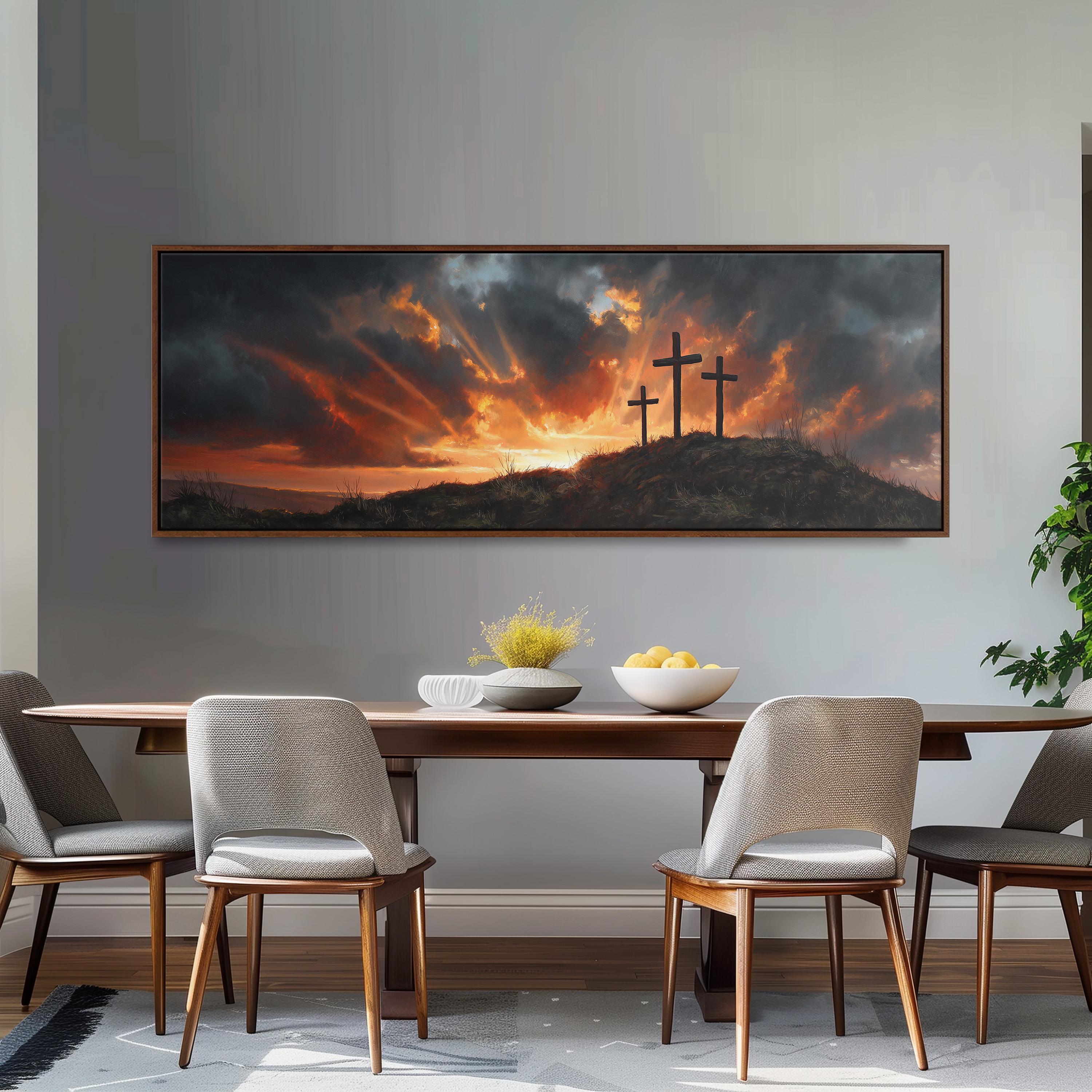 a large painting of a dramatic landscape with three crosses on a hill, set against a cloudy sky with a sunset. The painting is hung on a wall above a wooden dining table with four chairs.